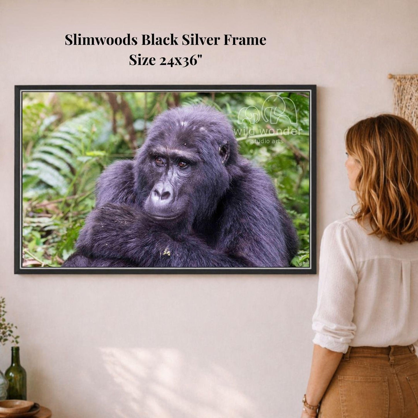 A woman is standing in front of a framed photograph of a gorilla, which is hanging on a wall.