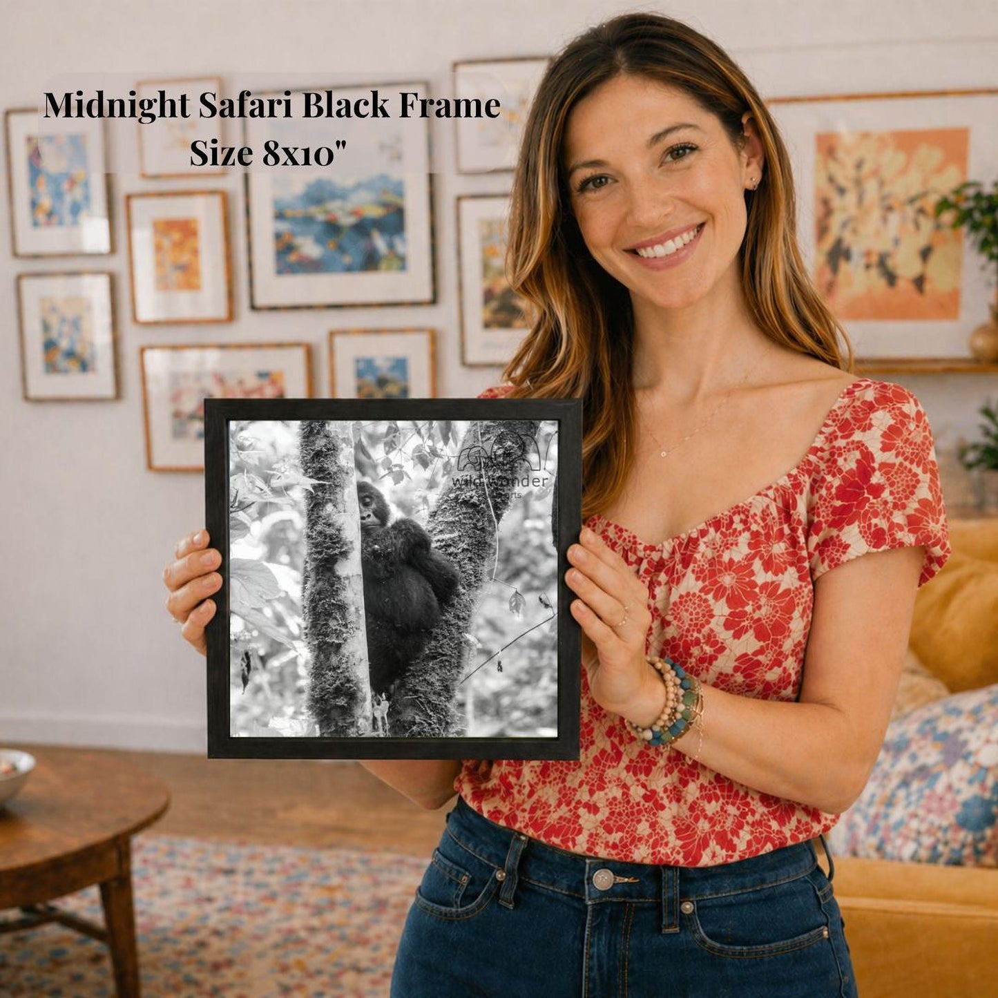 A woman is holding a framed photograph of a tree with a black and white image of a monkey on it, standing on a branch.