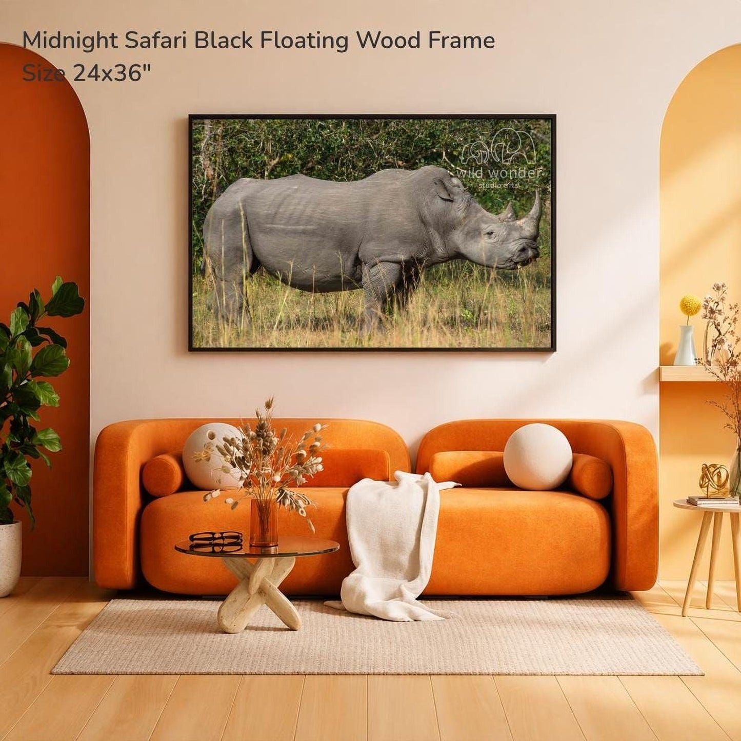 a large black floating wood frame with a photograph of a rhinoceros in a grassy field. The frame is hanging on a wall, and there is a couch and a coffee table in the foreground.
