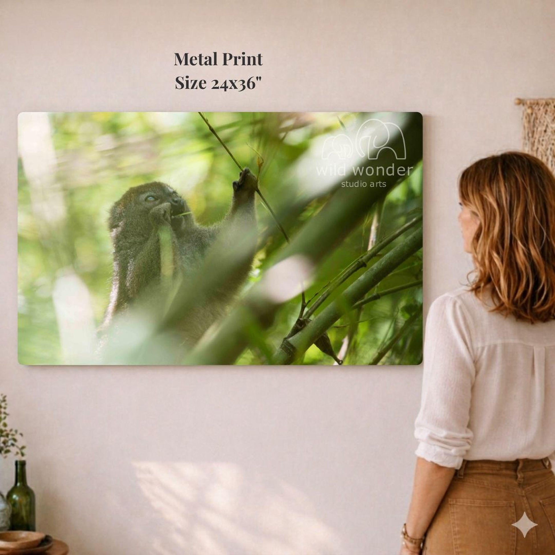 A woman is standing in front of a large metal print depicting a monkey in a lush, green forest setting.