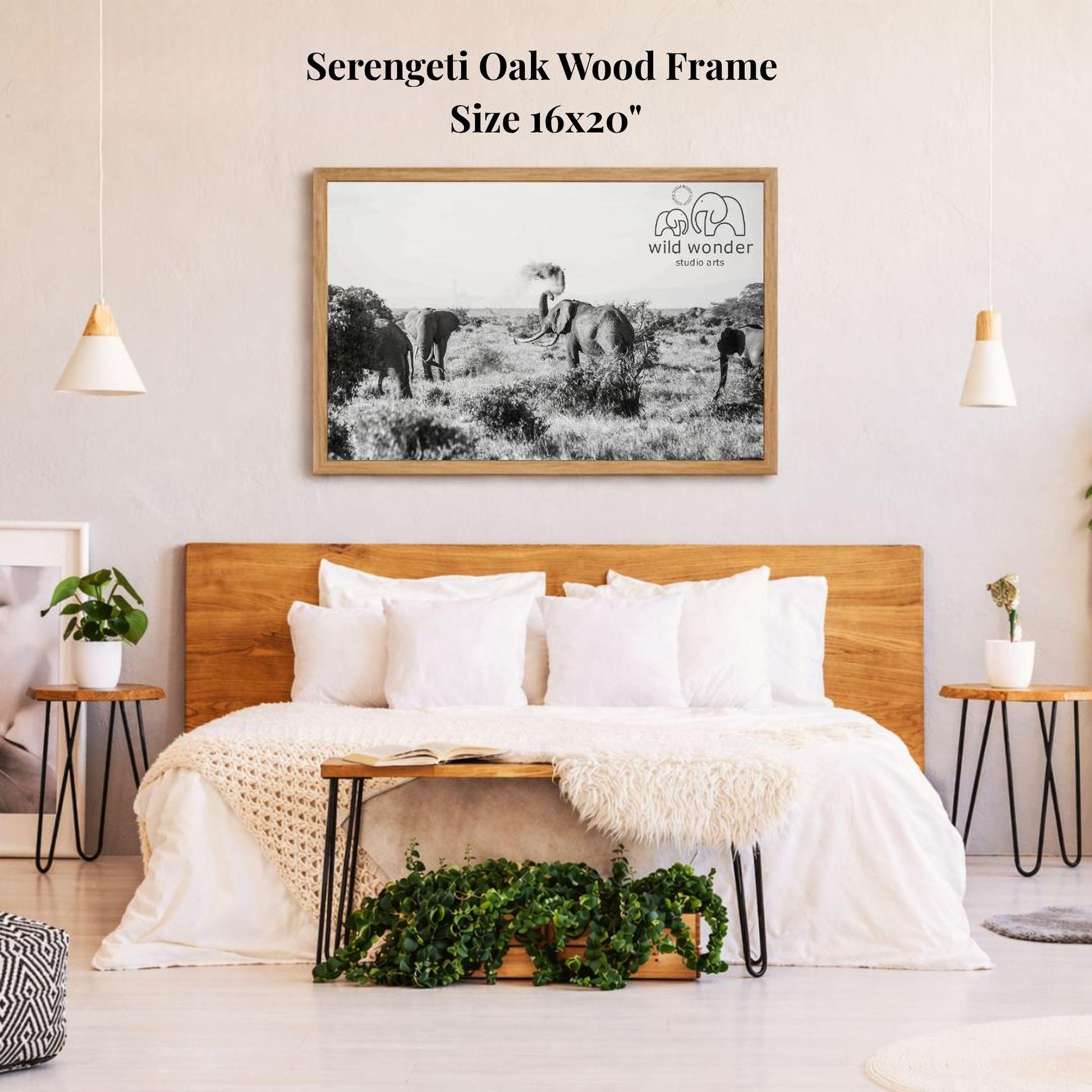 a serene bedroom setting with a large framed black and white photograph of elephants in a field hanging on the wall above a bed with white bedding.