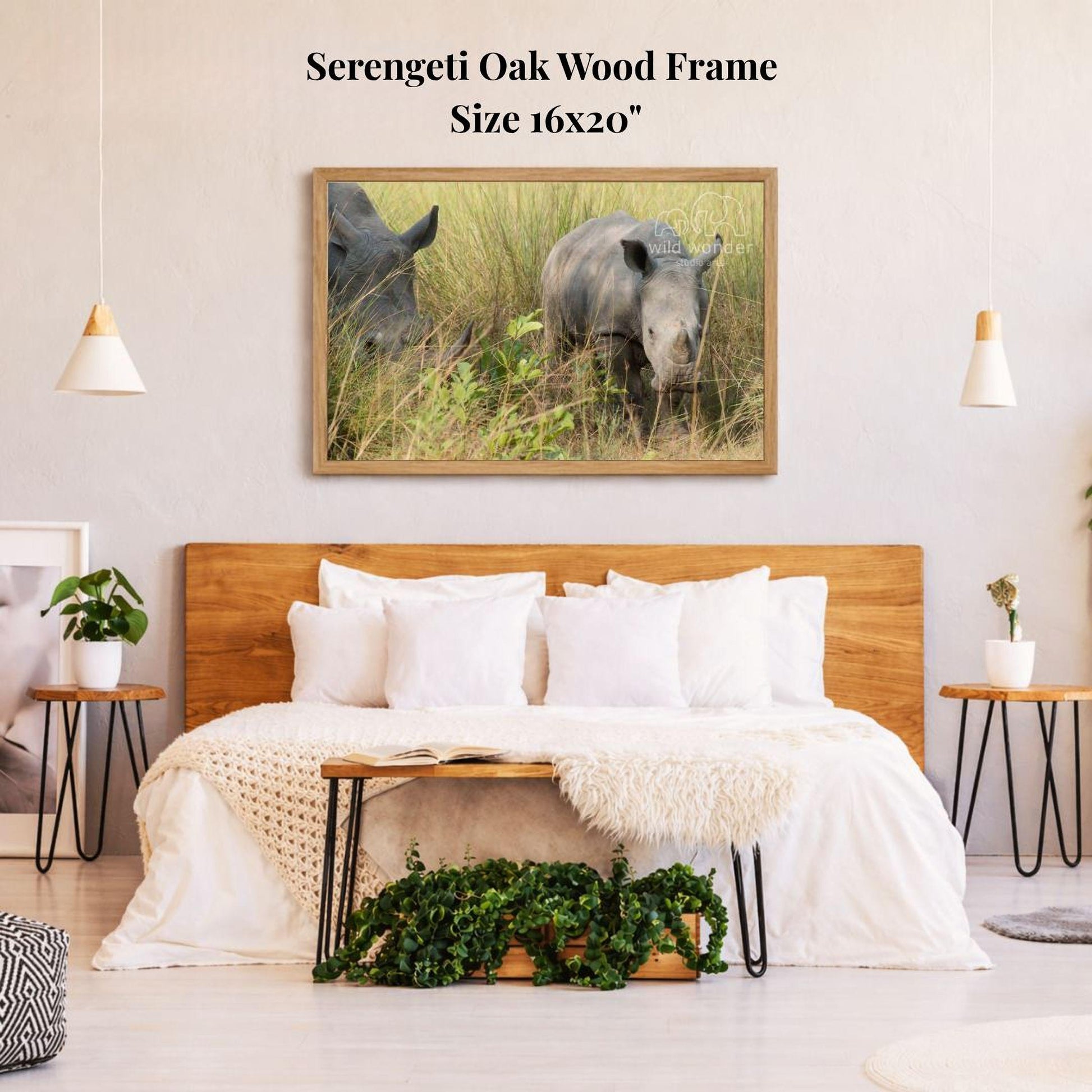 a serene bedroom scene with a large framed photograph of two rhinos grazing in the grass on the wall above a bed with white bedding.