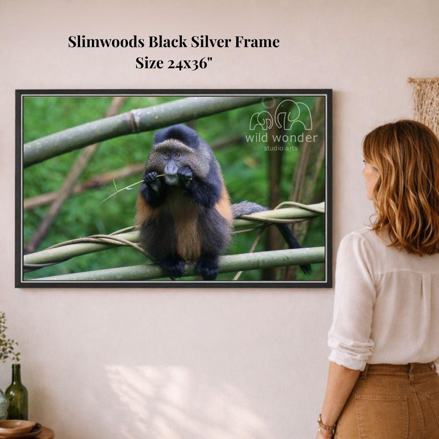 A woman is standing in front of a framed photograph of a monkey on a branch, looking at the artwork.