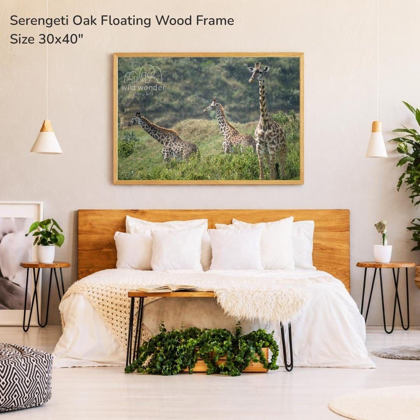 a serene bedroom setting with a large wooden headboard and a cozy bed. Above the bed, there is a framed photograph of three giraffes in a grassy field, creating a peaceful and natural atmosphere. The room is decorated with potted plants and other natural elements, adding to the overall ambiance.