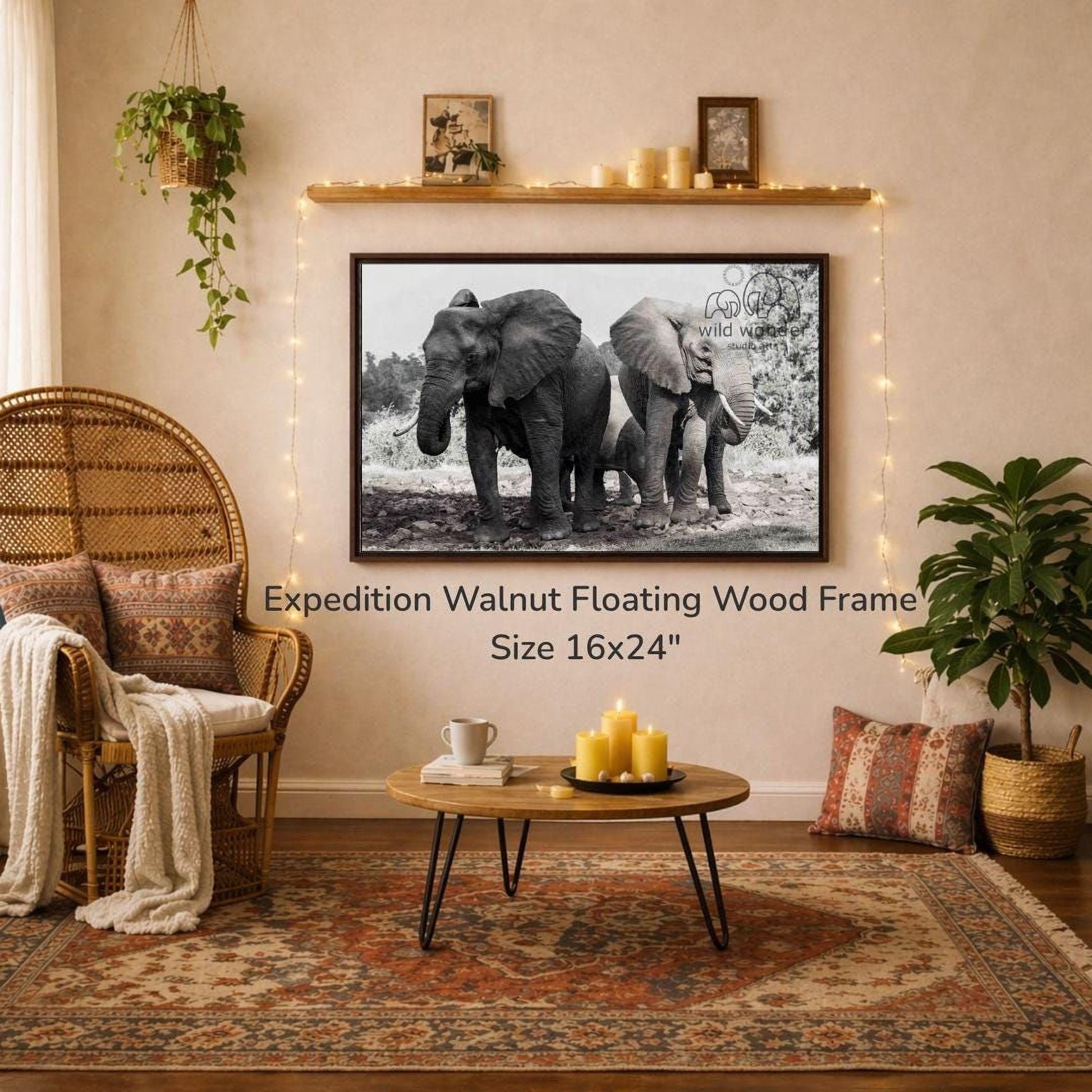 a large black and white photograph of two elephants standing next to each other, hanging on a wall above a coffee table in a cozy living room setting.
