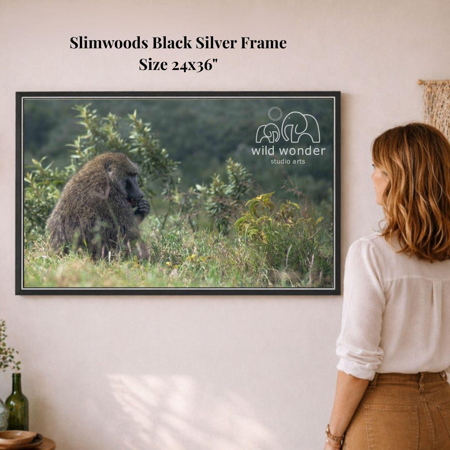 A woman is standing in front of a framed photograph of a gorilla in a lush, green environment.