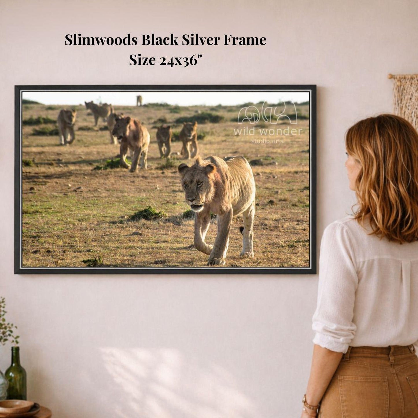 A woman is standing in front of a framed photograph of a group of lions in a grassy field.