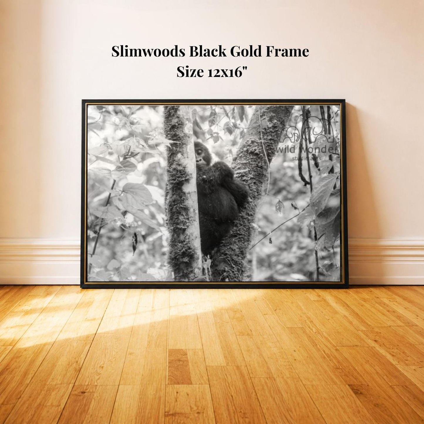 A black and white photograph of a baby gorilla sitting on a tree branch in a forest setting.