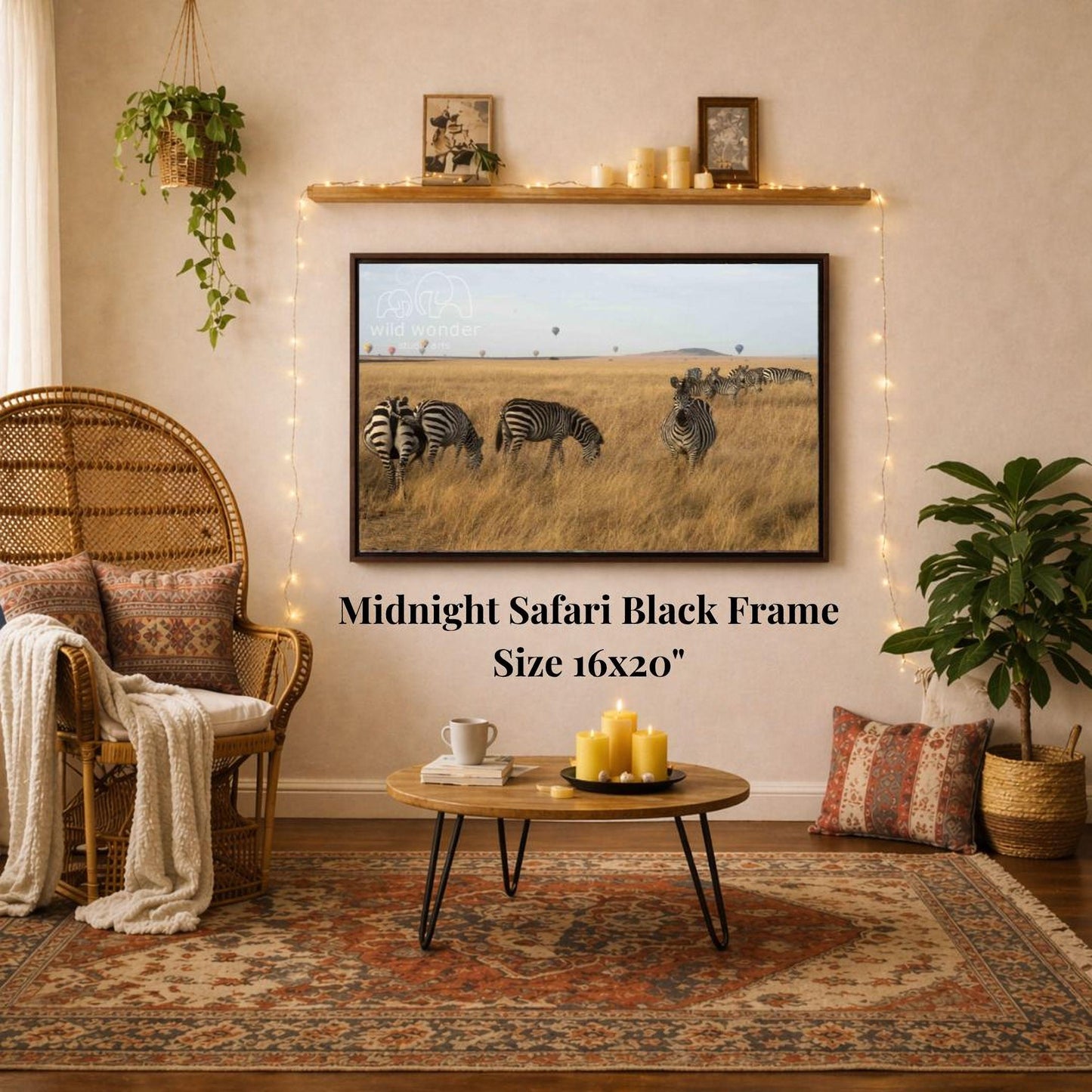 a living room with a large framed photograph of zebras in a grassy field hanging on the wall. The photograph is mounted on a black frame, which is described as a "Midnight Safari Black Frame" and is 16x20 inches in size. The room is decorated with a wicker chair, a coffee table, and a potted plant, creating a cozy and inviting atmosphere.