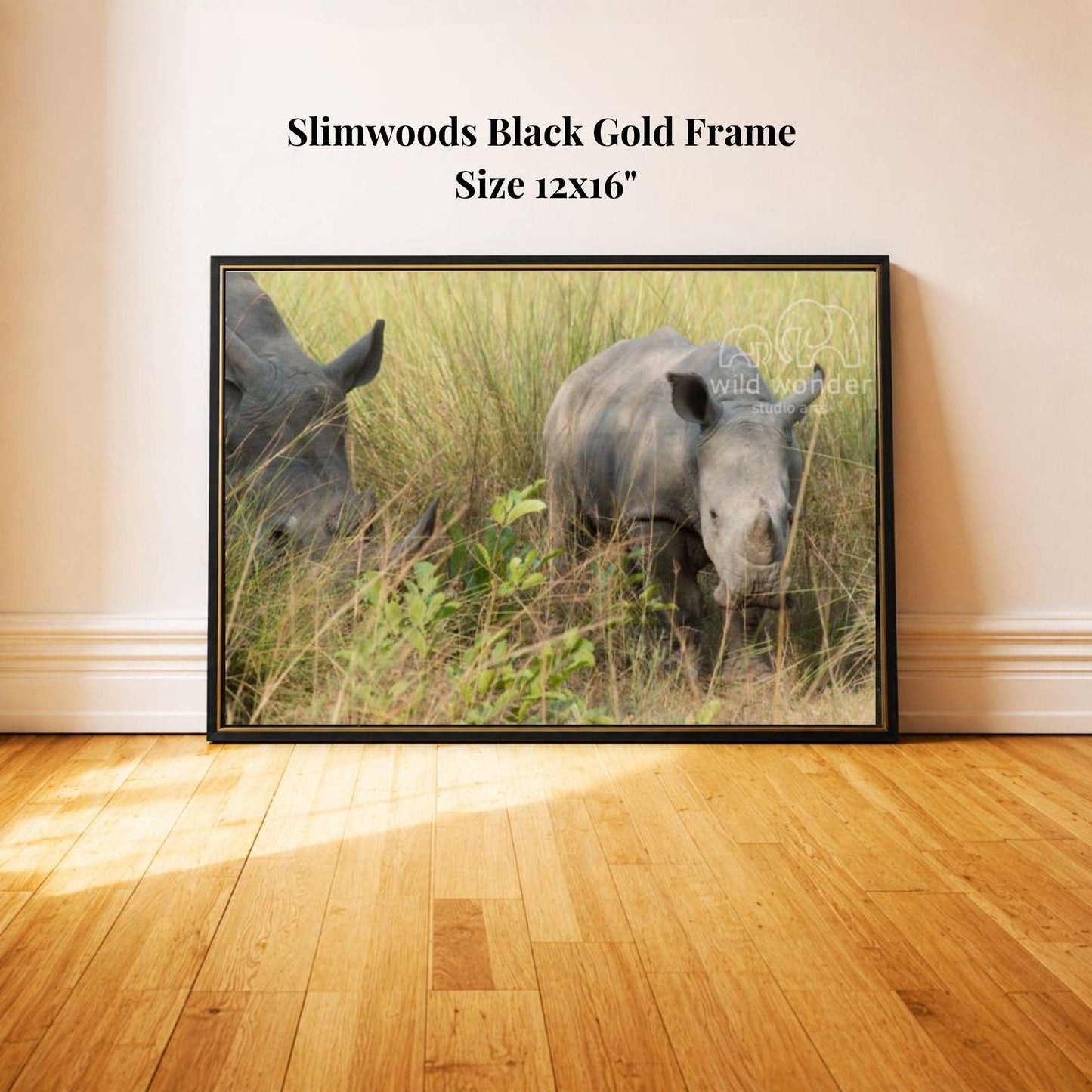 A black rhinoceros standing in tall grass, with a gold frame.
