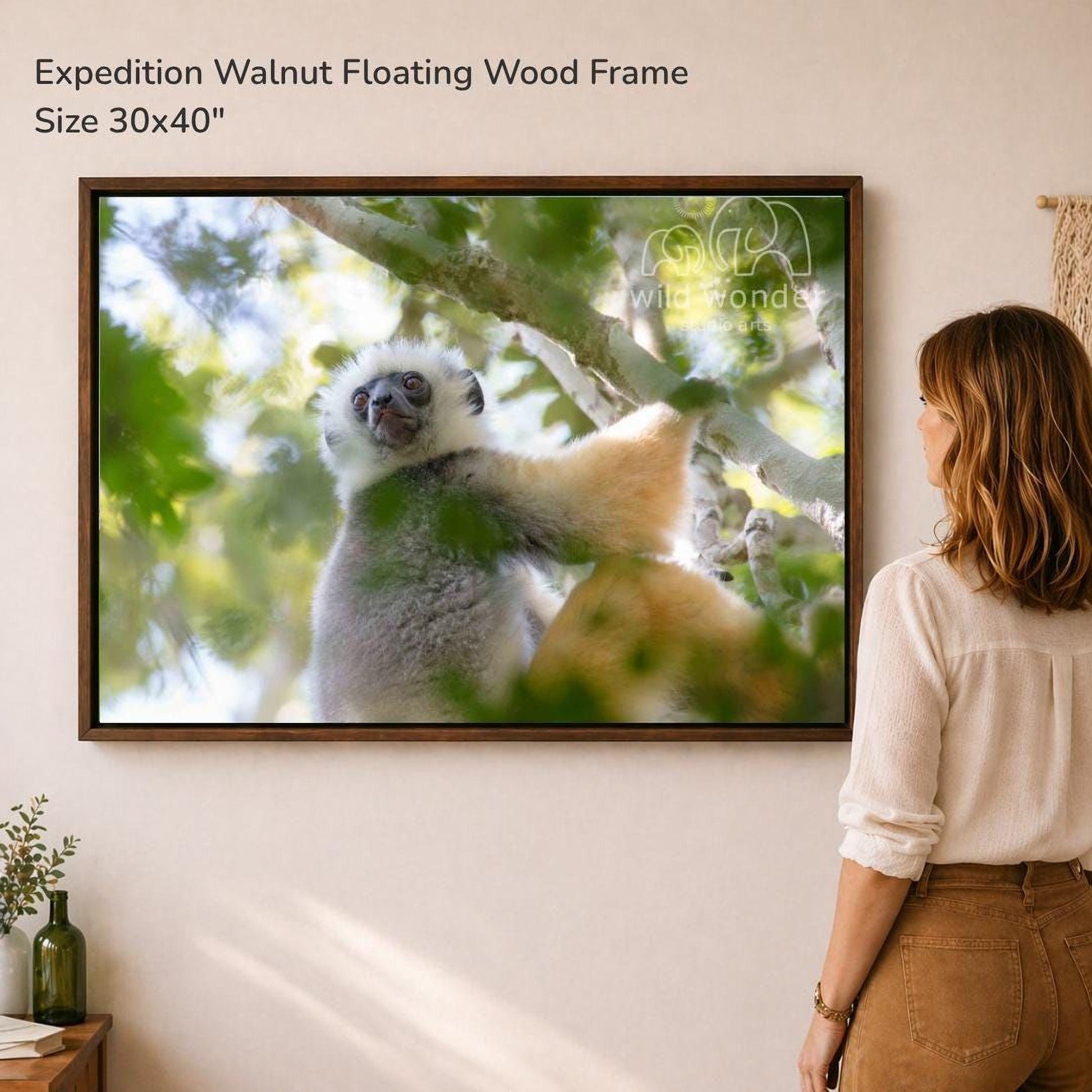 A woman is standing in front of a large framed photograph of a lemur, which is hanging on a wall.