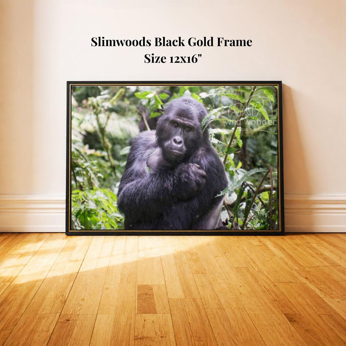 A black and gold framed photograph of a gorilla sitting in a lush, green forest environment.