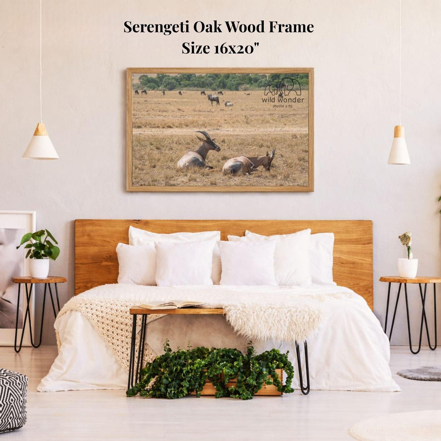 a serene bedroom scene with a large framed picture of a herd of antelopes resting in a field above a bed with white bedding.