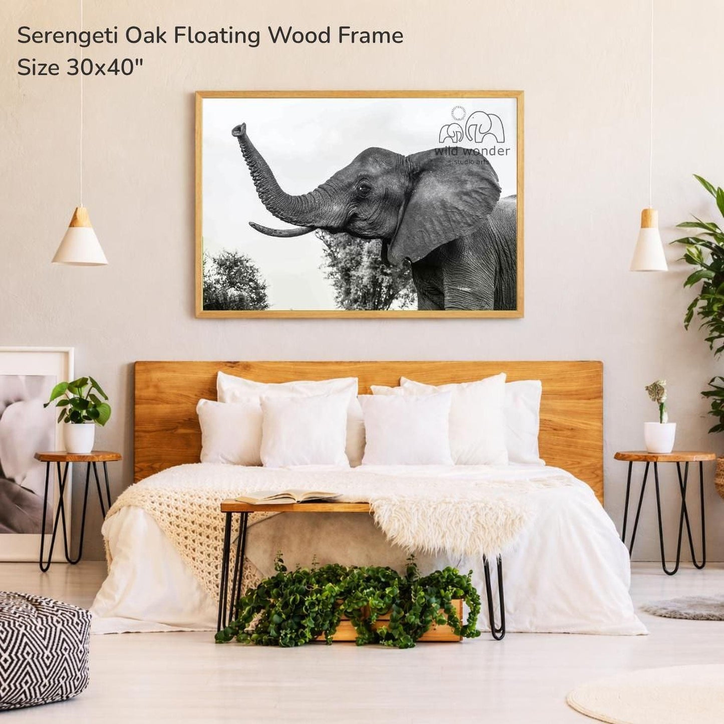 a bedroom with a large framed photograph of an elephant on the wall above a bed with white bedding. The room has a wooden headboard and a wooden nightstand on each side of the bed. There are also potted plants and other decorative elements in the room.