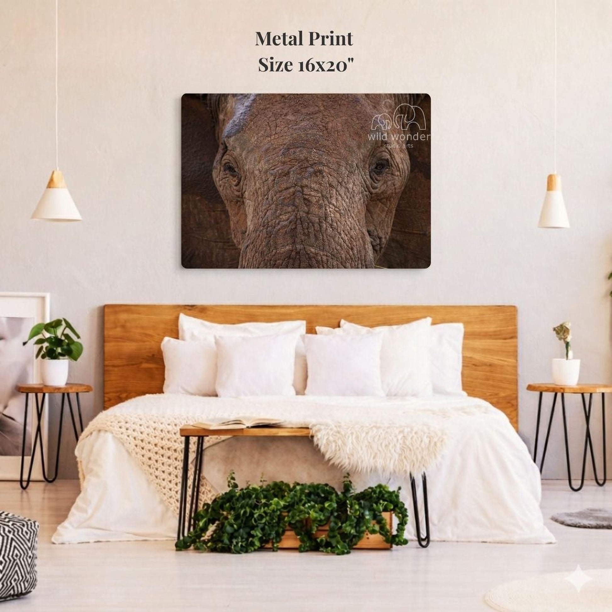 a large metal print of an elephant's face on a wall above a bed with white bedding and pillows.