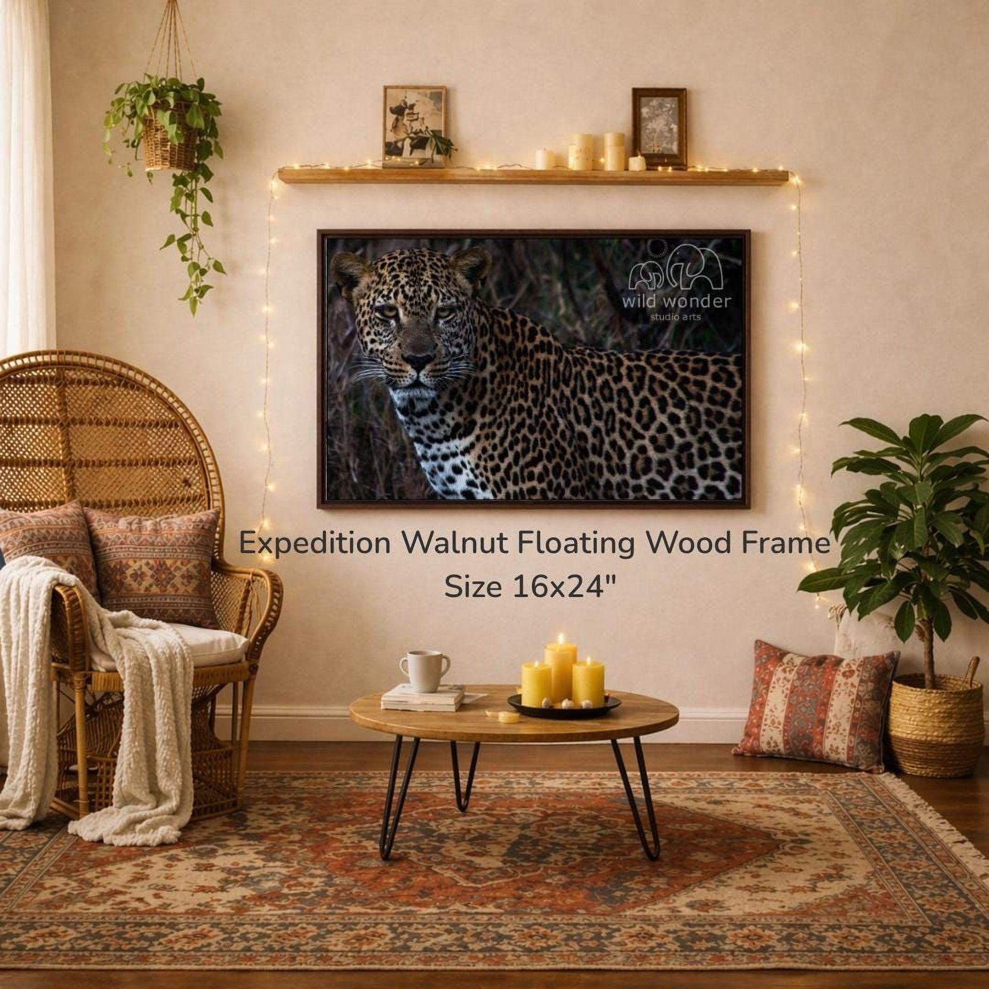 a large wall-mounted 16x24" walnut floating wood frame with a leopard print design, hanging above a coffee table with candles and a book. The room has a cozy and inviting atmosphere, with a wicker chair, a woven rug, and a potted plant.