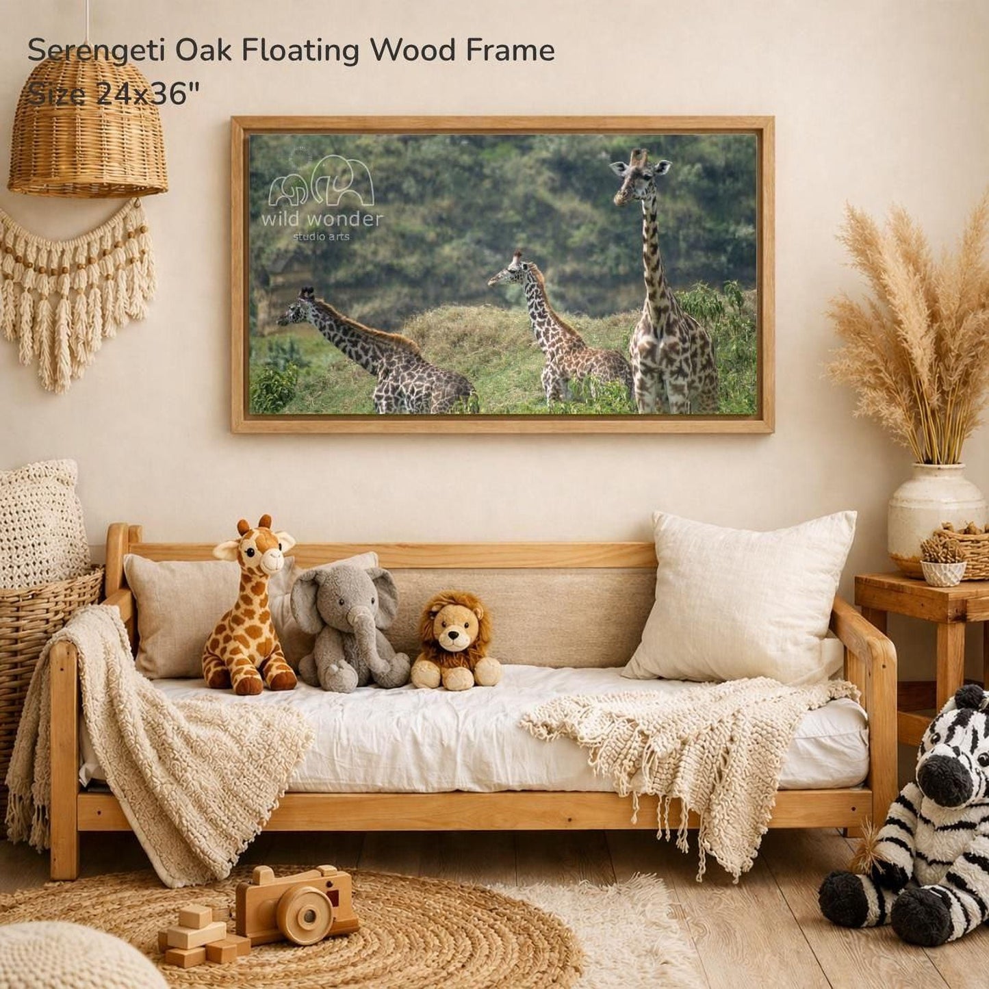 a serene indoor setting with a wooden frame hanging on a wall, displaying a photograph of a group of giraffes in a grassy field. The frame is described as a "Serengeti Oak Floating Wood Frame" and measures 24" x 36". The room is decorated with various items, including a wooden bench, a stuffed elephant, a wooden toy camera, and a stuffed zebra.