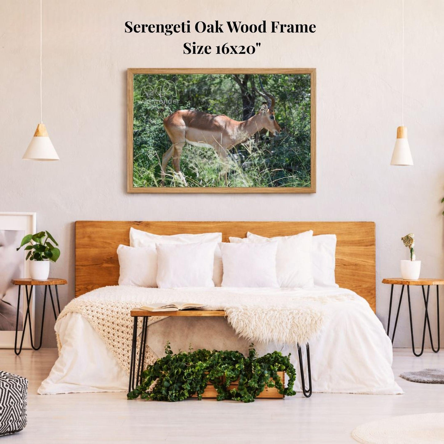 a serene bedroom scene with a large framed photograph of a deer standing in a lush green forest on the wall above a bed with white bedding.