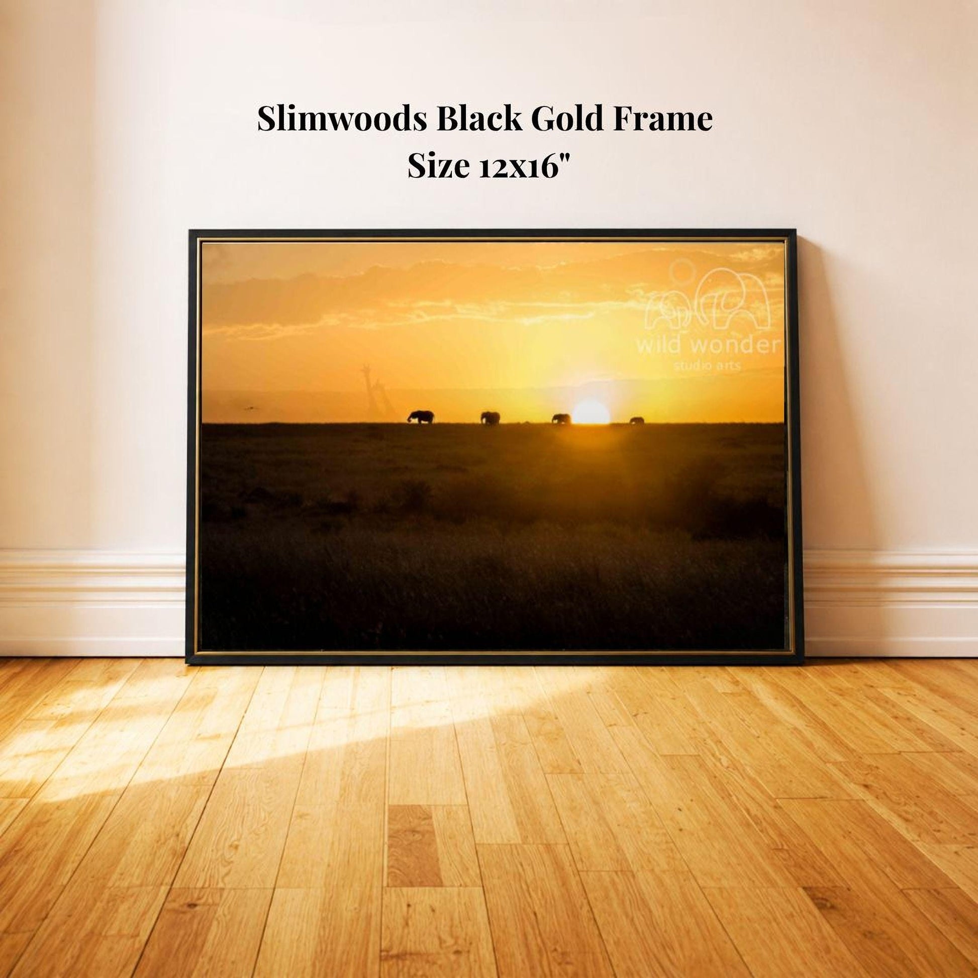 A framed photograph of a sunset over a grassy field, with silhouettes of animals in the distance.