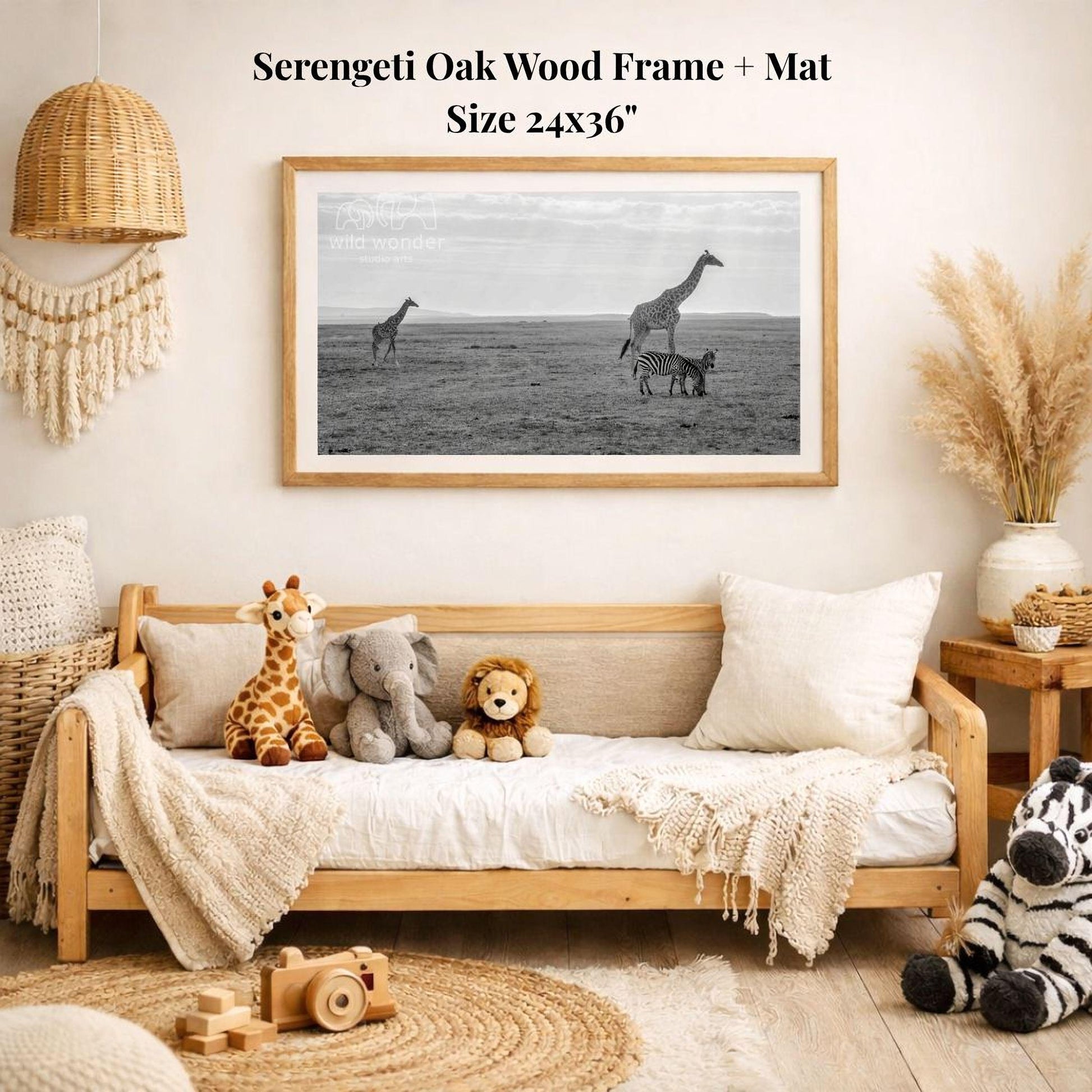 a serene indoor setting with a wooden frame and mat hanging on the wall, displaying a black and white photograph of three giraffes and a zebra in a field. The frame is surrounded by various stuffed animals, including a giraffe, an elephant, and a lion, creating a cozy and playful atmosphere.