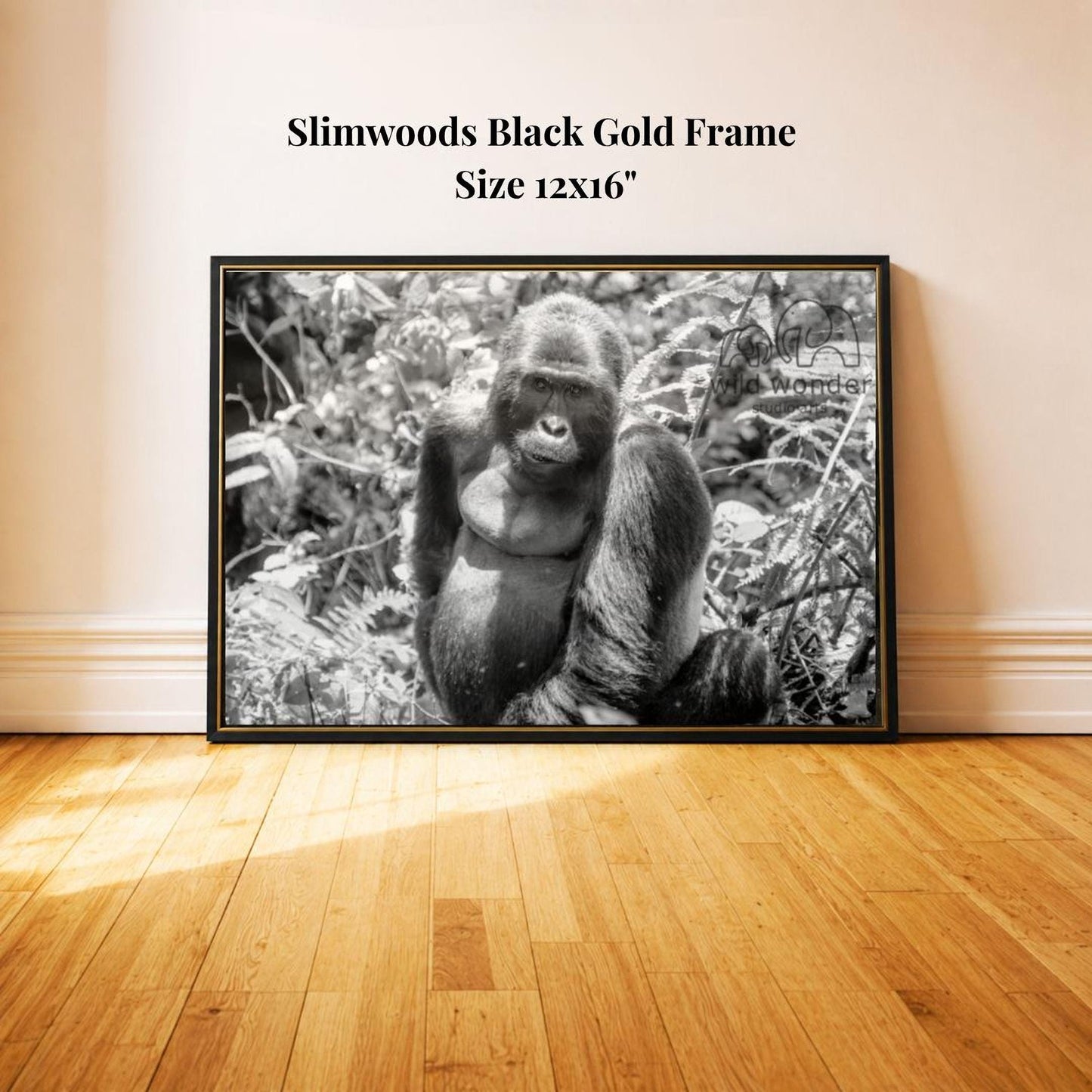A black and white photograph of a gorilla sitting in a natural setting, with a black frame around it.