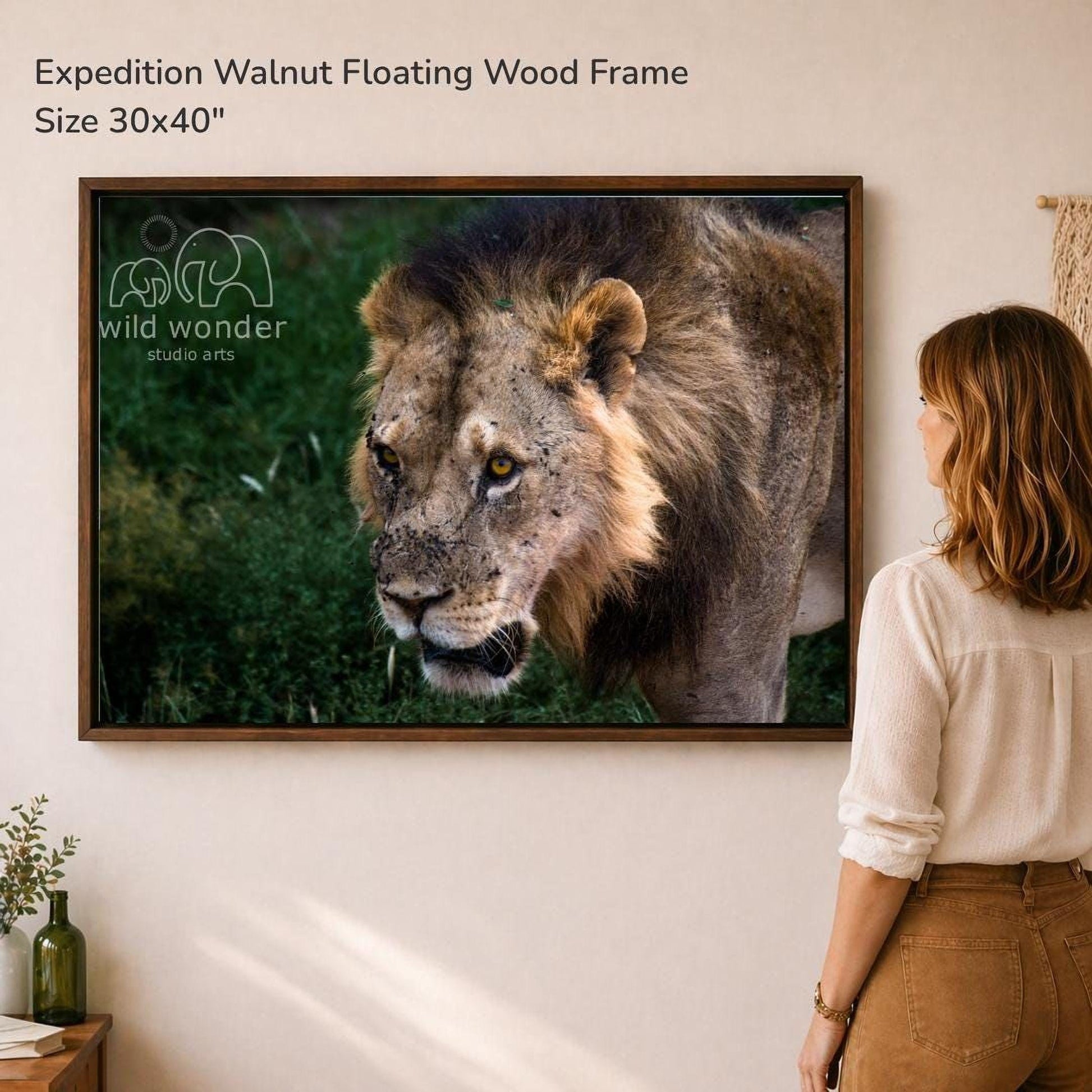 A woman is standing in front of a large framed photograph of a lion, which is hanging on a wall.