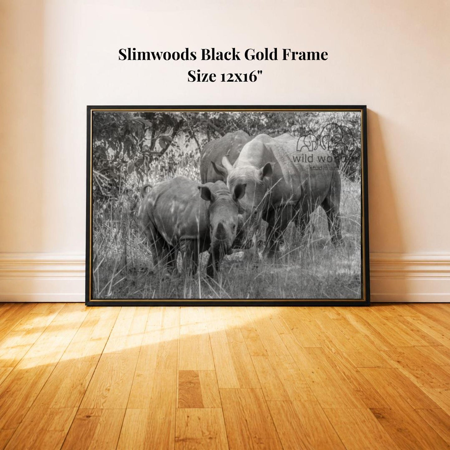 A black and white photograph of two rhinos standing in a grassy area, with a text overlay indicating the frame is a "Slimwoods Black Gold Frame" and the size is 12x16 inches.