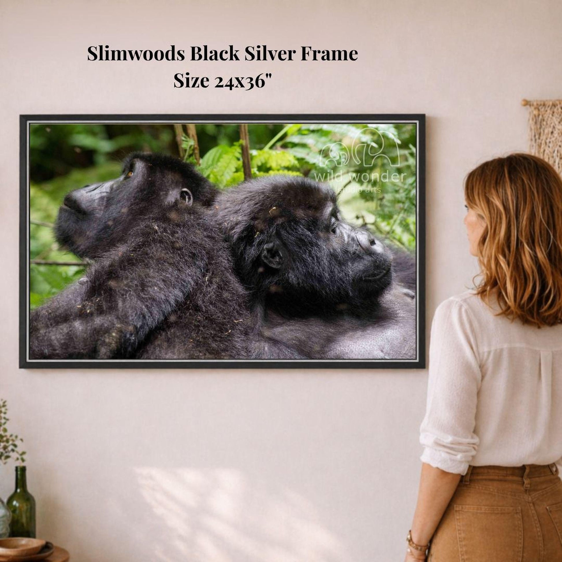 A woman is standing in front of a framed photograph of two gorillas, which is hanging on a wall.