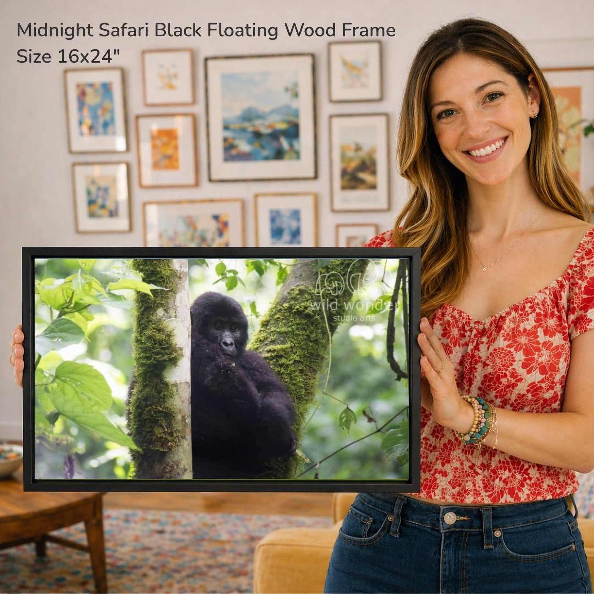A woman is holding a framed photograph of a gorilla in a tree, with a smiling expression.