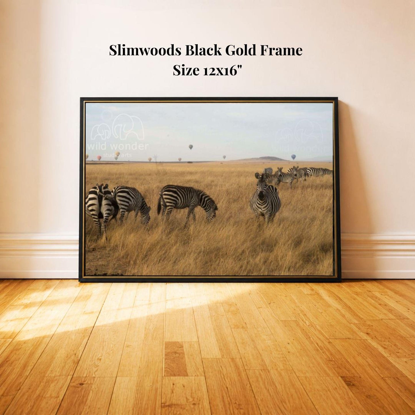 A framed photograph of a group of zebras grazing in a grassy field, with a black gold frame and a size of 12x16 inches.
