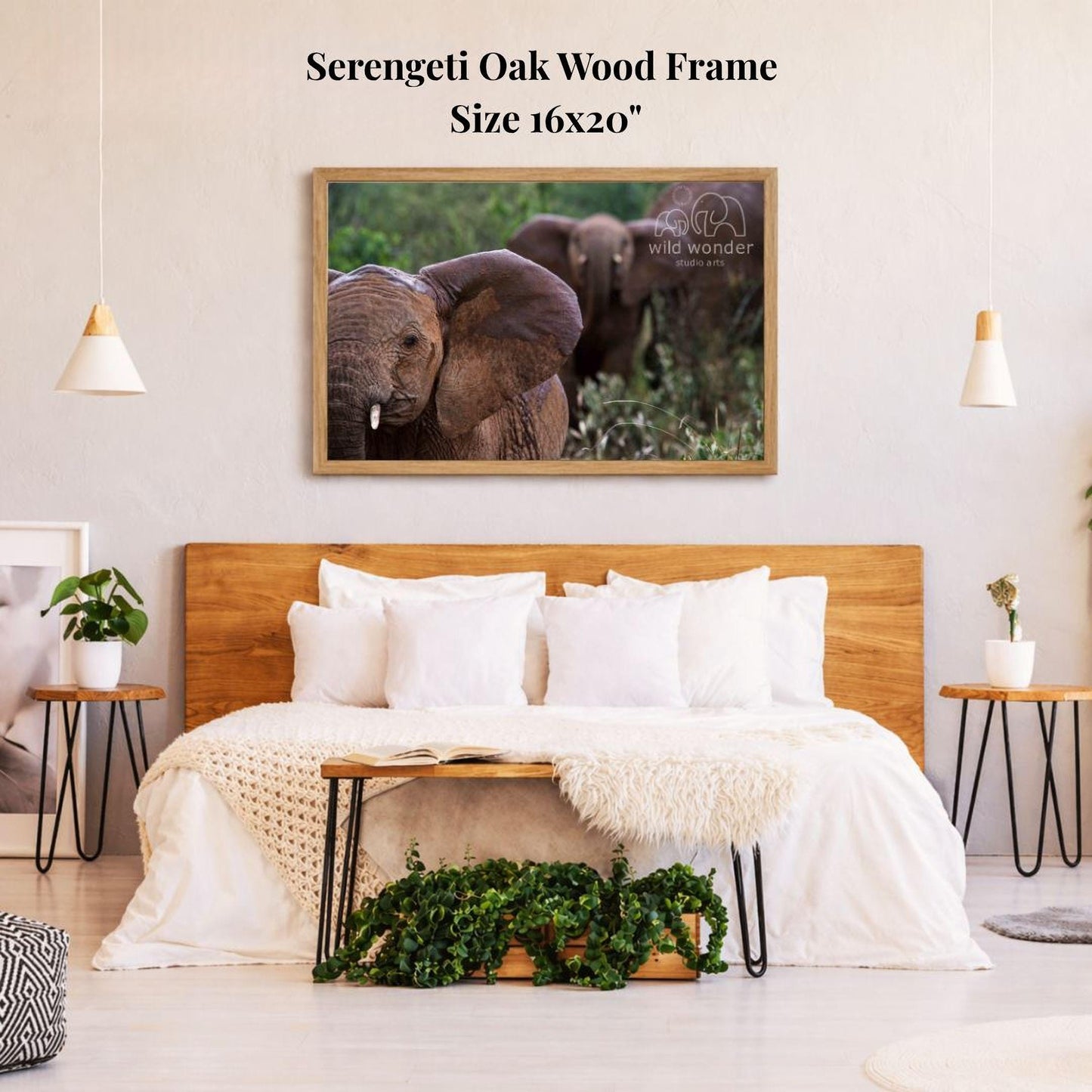 a serene bedroom scene with a large framed photograph of two elephants on the wall above a bed with white bedding. The room has a wooden headboard and a wooden nightstand on each side of the bed, with a potted plant and a small plant on the nightstands. The overall decor has a natural and calming aesthetic.