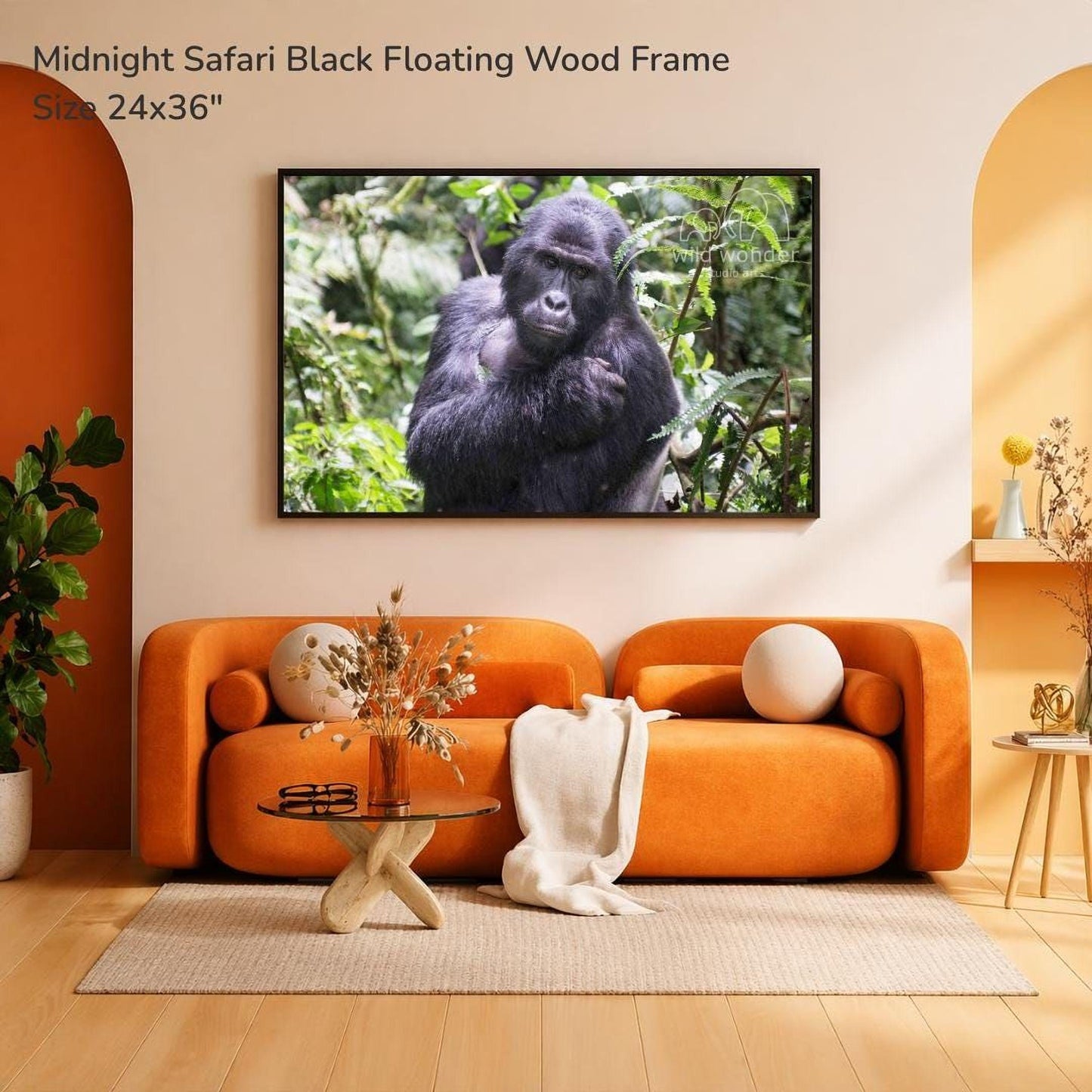 a large black gorilla sitting in a lush, green forest environment, mounted on a wall above a cozy living room setting with an orange sofa, a glass coffee table, and a potted plant.