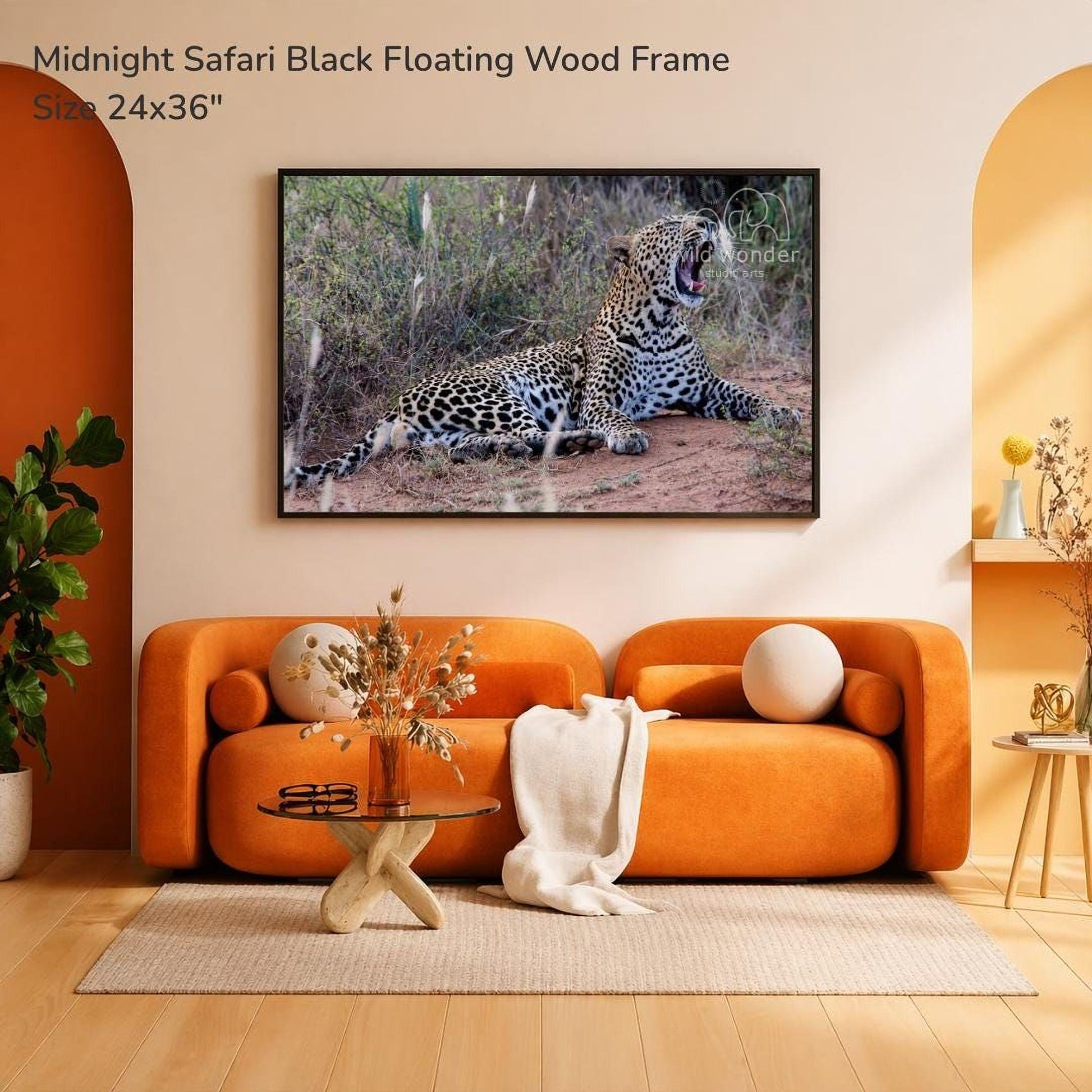 a large black floating wood frame with a photograph of a leopard resting on the ground, hanging on a wall in a living room setting.