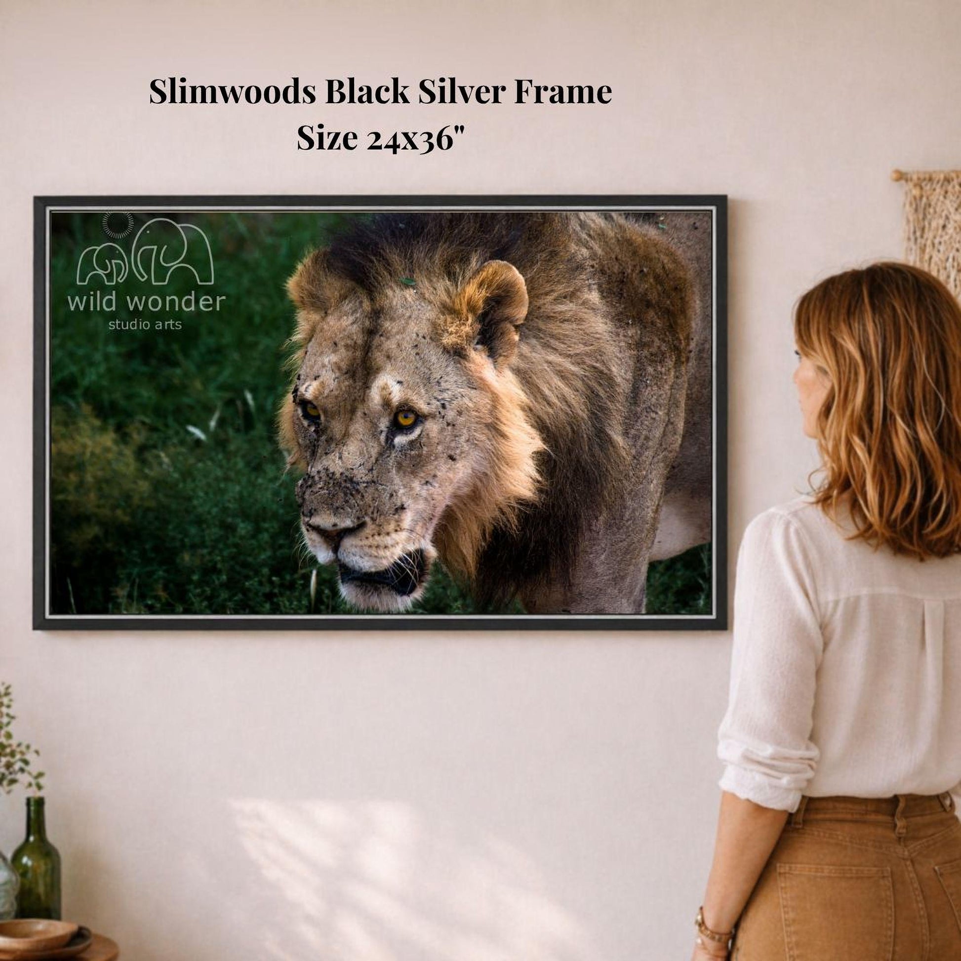 A woman is standing in front of a framed photograph of a lion, which is hanging on a wall.