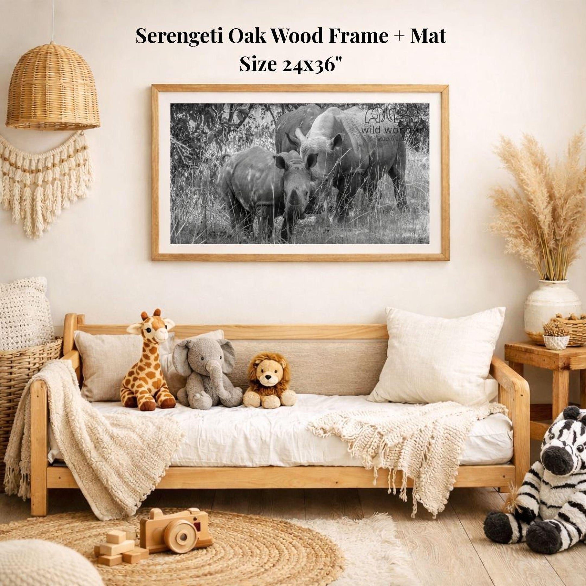 a serene indoor setting with a wooden frame and mat hanging on the wall, displaying a black and white photograph of two elephants. The frame is surrounded by various stuffed animals, including a giraffe, an elephant, and a lion, creating a cozy and playful atmosphere.