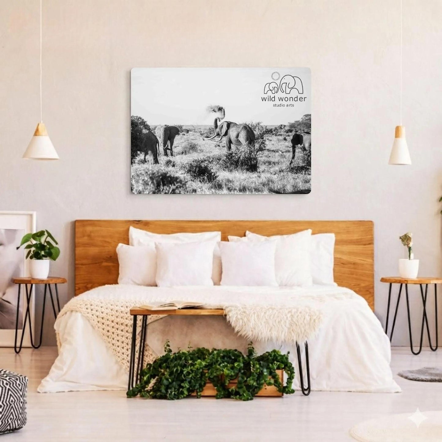 a bedroom with a large metal print of a black and white photograph of elephants in a field hanging on the wall above a bed with white bedding.