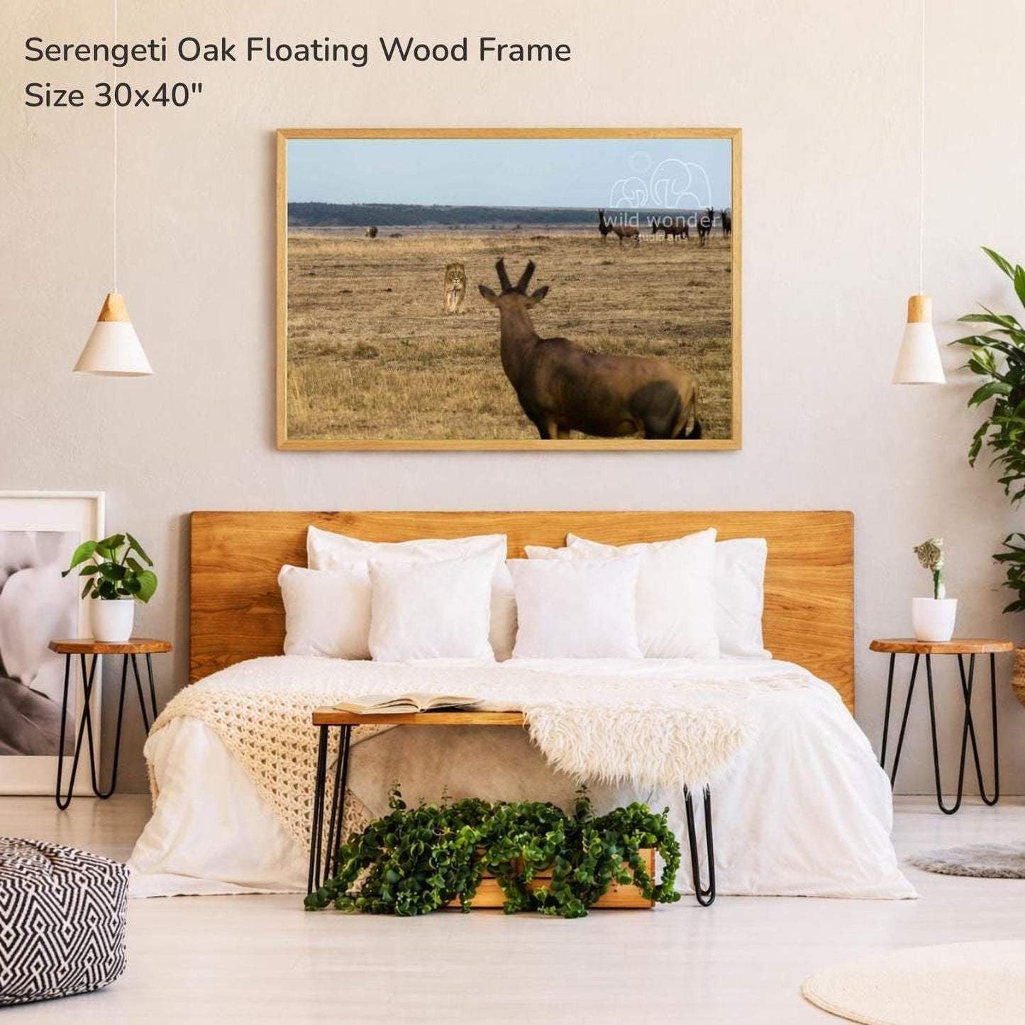 a serene bedroom setting with a large bed, a wooden headboard, and a framed photograph of a serene landscape with a herd of antelope in the background.