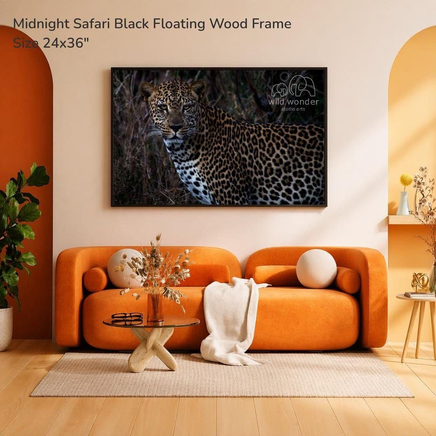 a large black floating wood frame with a photograph of a leopard on the wall, hanging above an orange sofa with a glass coffee table in front of it.