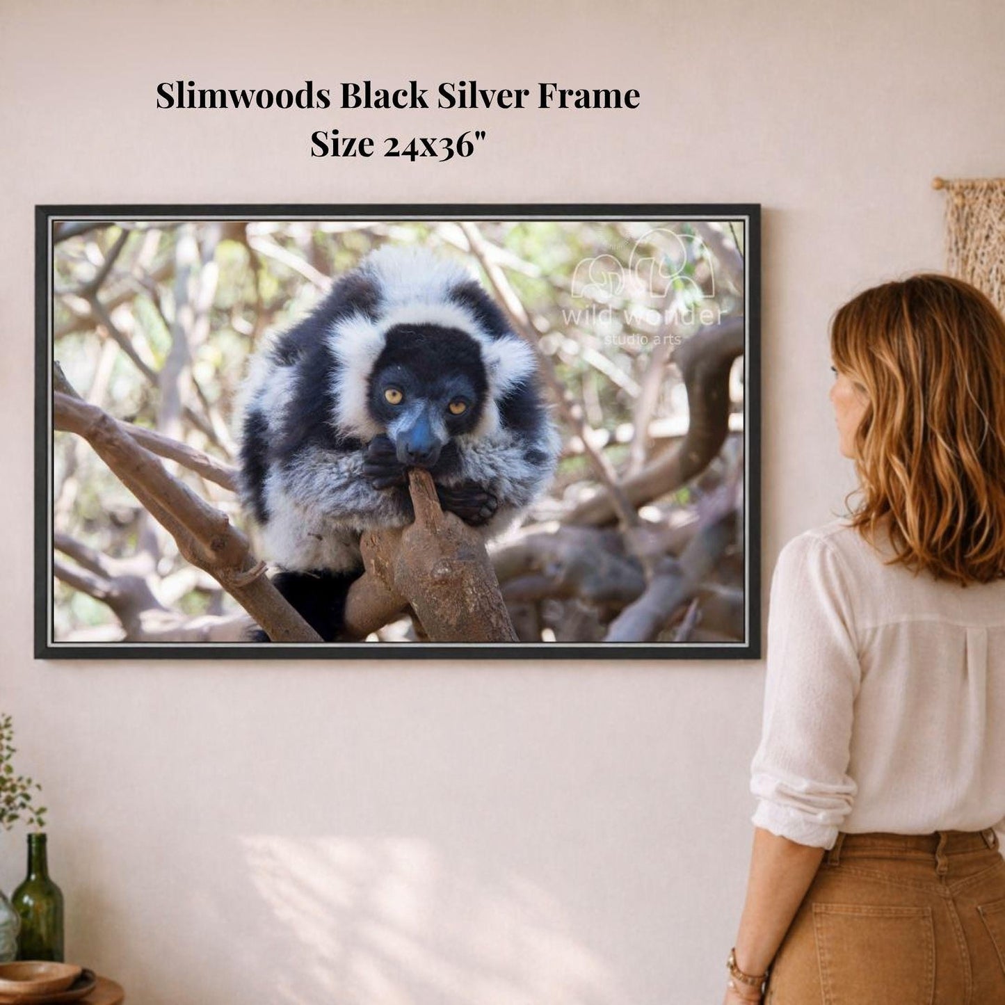 A woman is standing in front of a framed photograph of a lemur, which is a type of primate, in a forest setting.