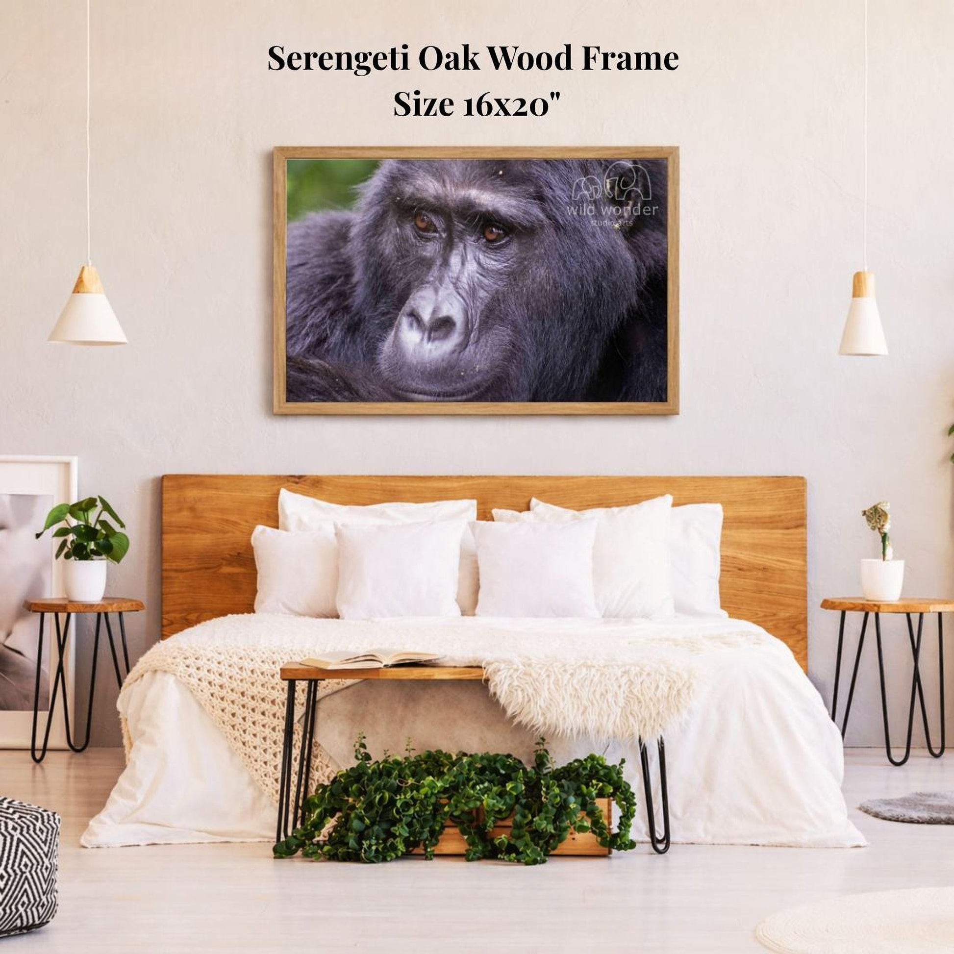 a bedroom with a large wooden headboard and a cozy bed with white bedding. Above the bed, there is a framed photograph of a gorilla, which appears to be the focal point of the room. The room has a minimalist and modern design, with pendant lights hanging above the bed and a plant on a side table.