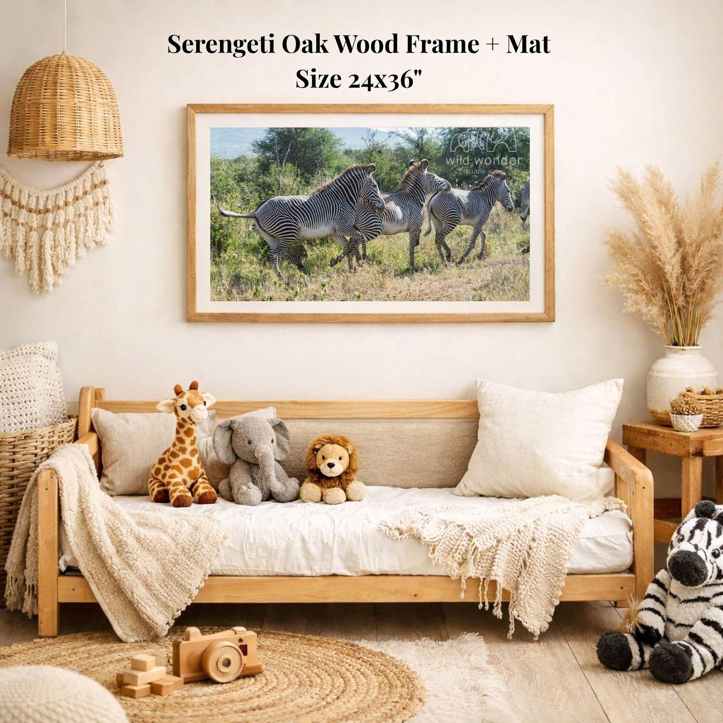a serene indoor setting with a wooden frame and mat hanging on a wall, displaying a photograph of a group of zebras in a grassy field. The room is decorated with various stuffed animals, including a giraffe, elephant, lion, and zebra, arranged on a couch and a rug. The overall atmosphere of the room appears to be cozy and inviting, with a focus on nature and wildlife.