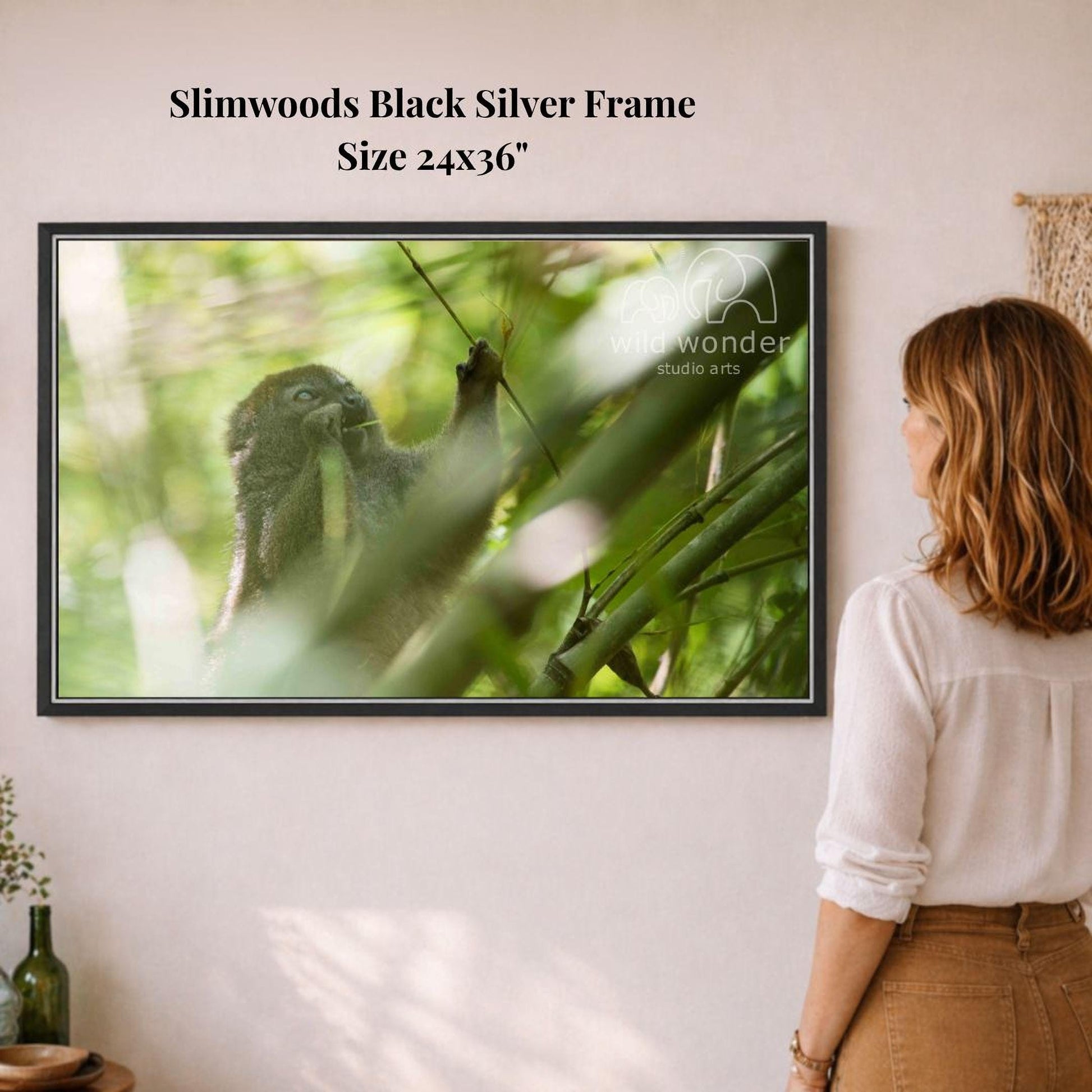A woman is standing in front of a framed photograph of a monkey in a lush, green forest, observing the scene.