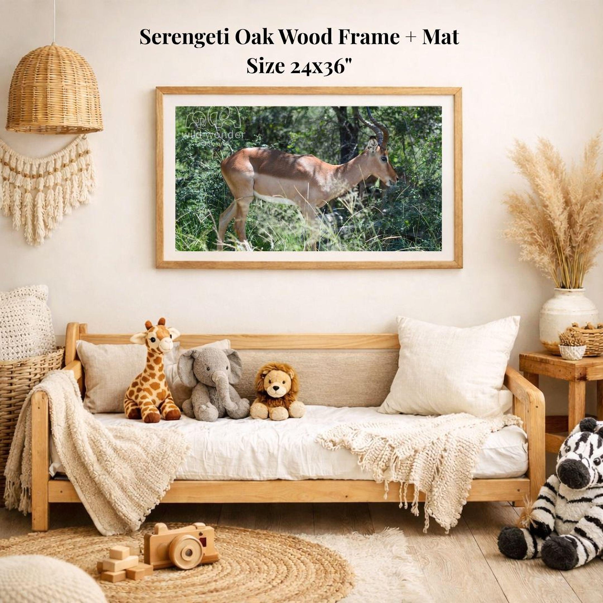 a serene indoor setting with a framed photograph of a deer in a wood frame hanging on a wall. The deer is surrounded by lush greenery, creating a peaceful and natural atmosphere. The photograph is framed in a 24x36" size, and the room is decorated with various items, including a sofa with stuffed animals, a woven basket, and a potted plant.