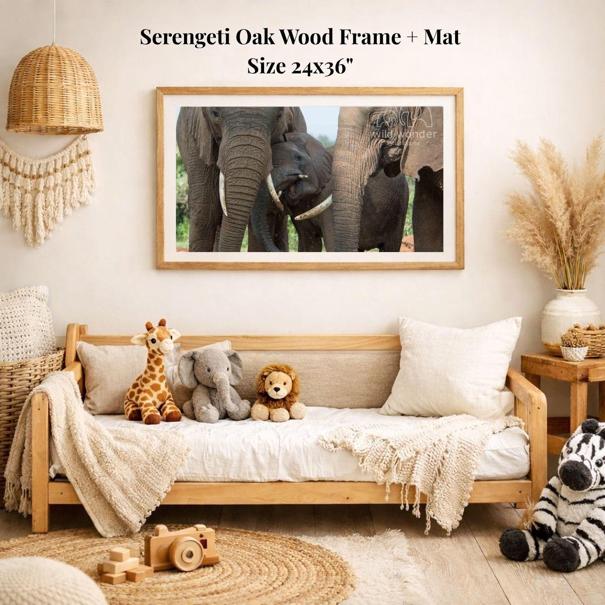 a serene indoor setting with a wooden frame and mat hanging on a wall, displaying a photograph of elephants. The room is decorated with various stuffed animals, including a giraffe, lion, and zebra, arranged on a couch and a bed. A wooden toy camera is also present in the scene.