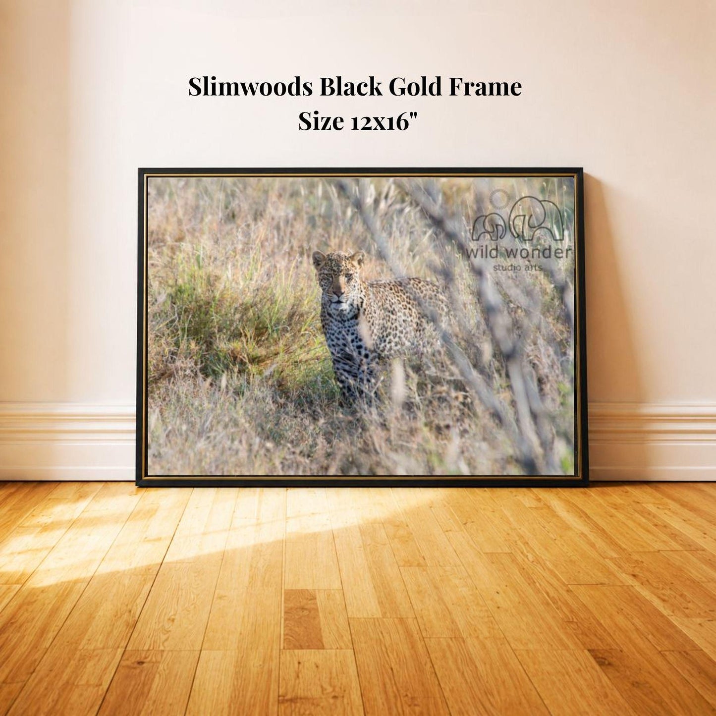 A framed photograph of a leopard standing in tall grass, with a black frame and text indicating the size of the frame as 12x16 inches.