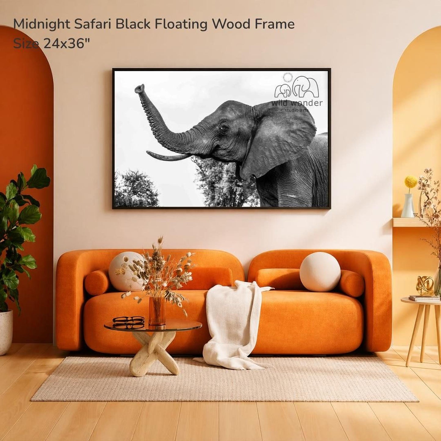 a large black and white photograph of an elephant, hanging on a wall above an orange sofa in a living room setting.