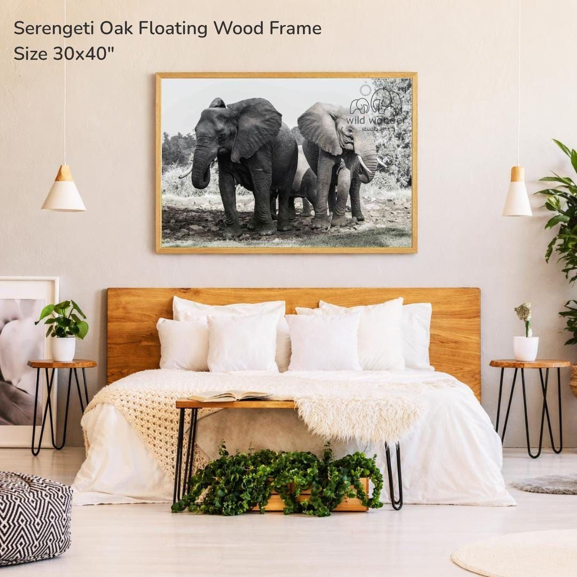 a bedroom with a large framed photograph of two elephants on the wall above a bed with white bedding.