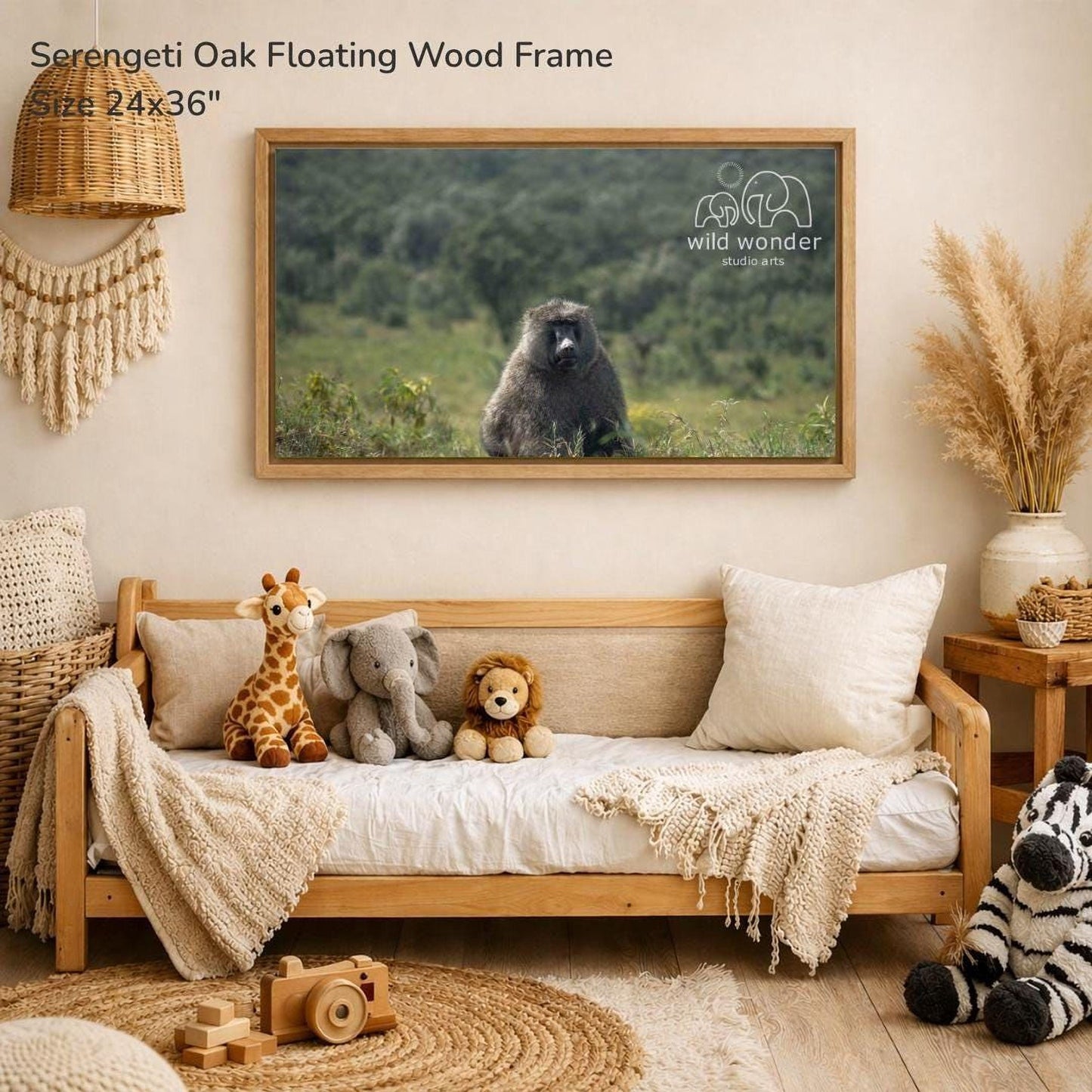 a serene indoor setting with a wooden frame hanging on a wall, displaying a photograph of a serene forest scene with a large elephant and a smaller elephant. The frame is described as a "Serengeti Oak Floating Wood Frame" and is 24" wide. The room also contains a couch with stuffed animals, a wooden toy car, and a woven basket, creating a cozy and inviting atmosphere.