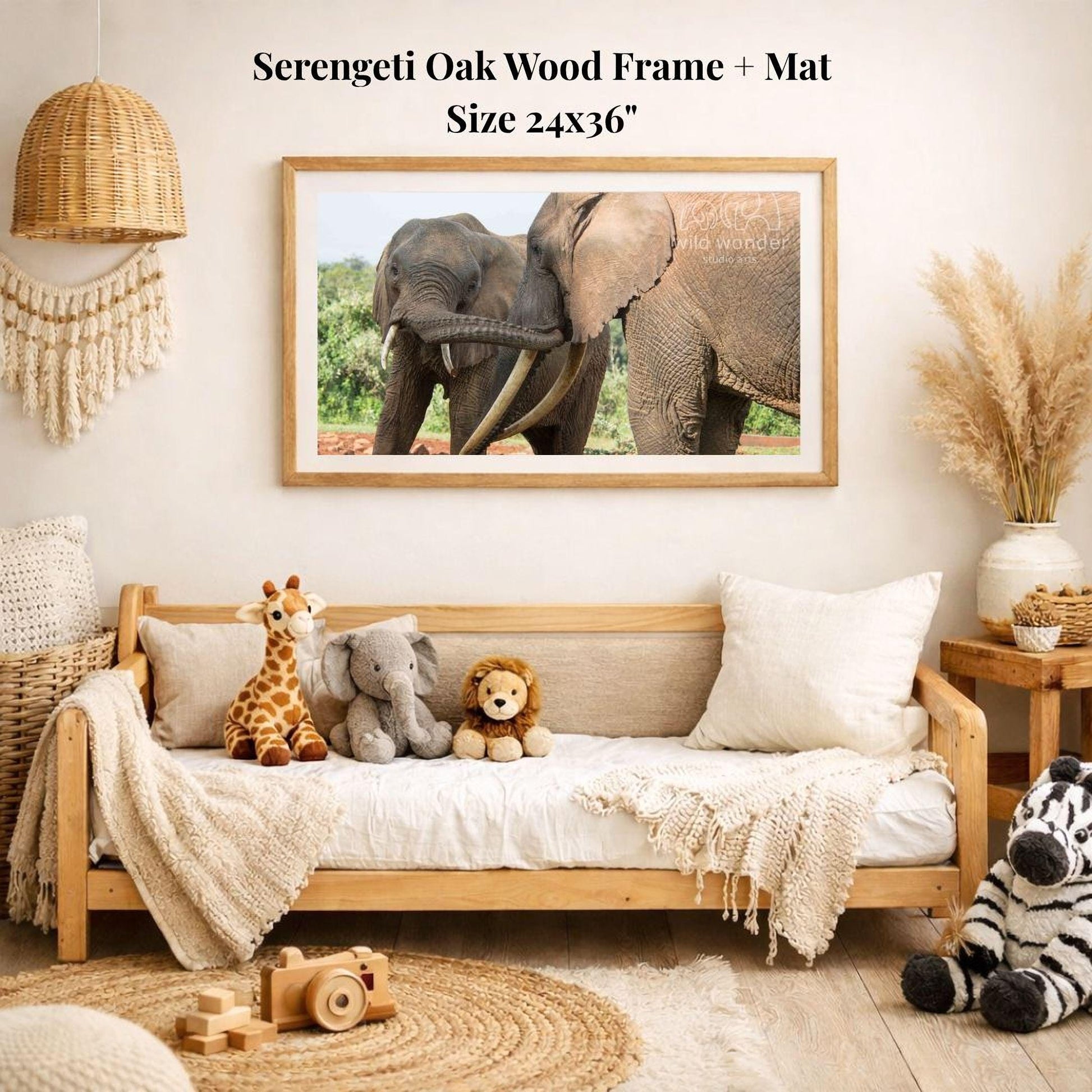 a serene indoor setting with a wooden frame and mat hanging on the wall, displaying a photograph of two elephants. The frame is surrounded by various stuffed animals, including a giraffe, an elephant, and a lion, creating a cozy and playful atmosphere.