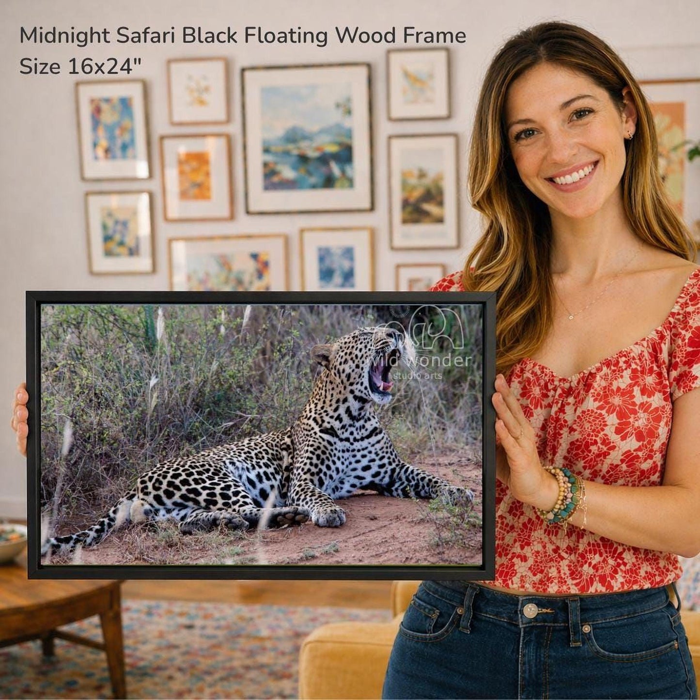 A woman is holding a framed photograph of a leopard in its natural habitat, with a smiling expression.